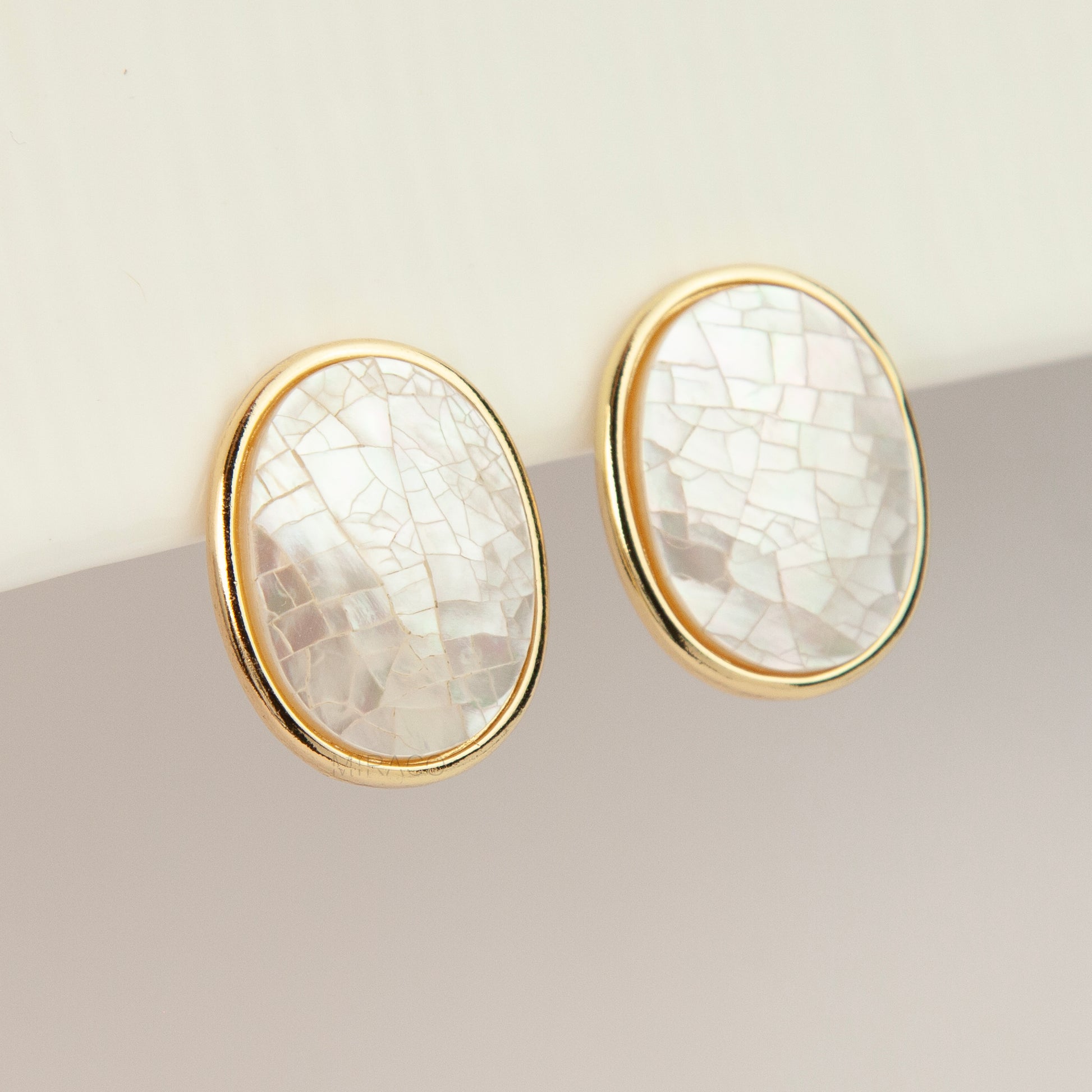 Pair of oval gold-tone non-pierced clip-on earrings with mini clip backs, set with iridescent white mother of pearl shell mosaic inlay.