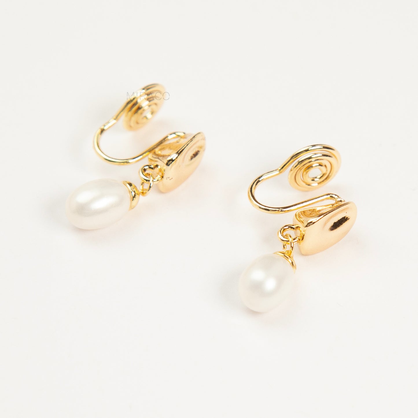 Pair of Gold-Tone Dangle Freshwater Pearl Clip-On Earrings with Coil Back closure.