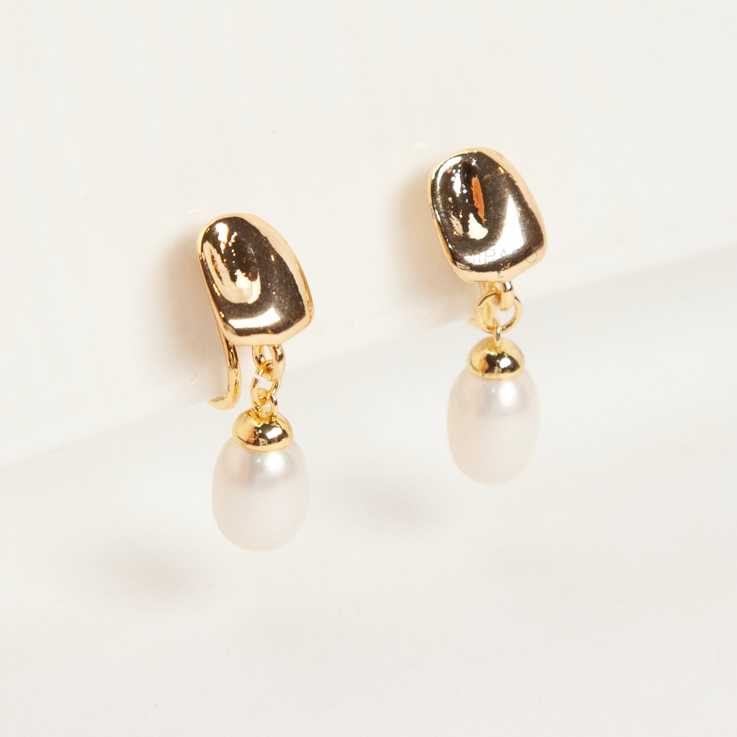 Pair of Gold-Tone Dangle Freshwater Pearl Clip-On Earrings with Coil Back closure.