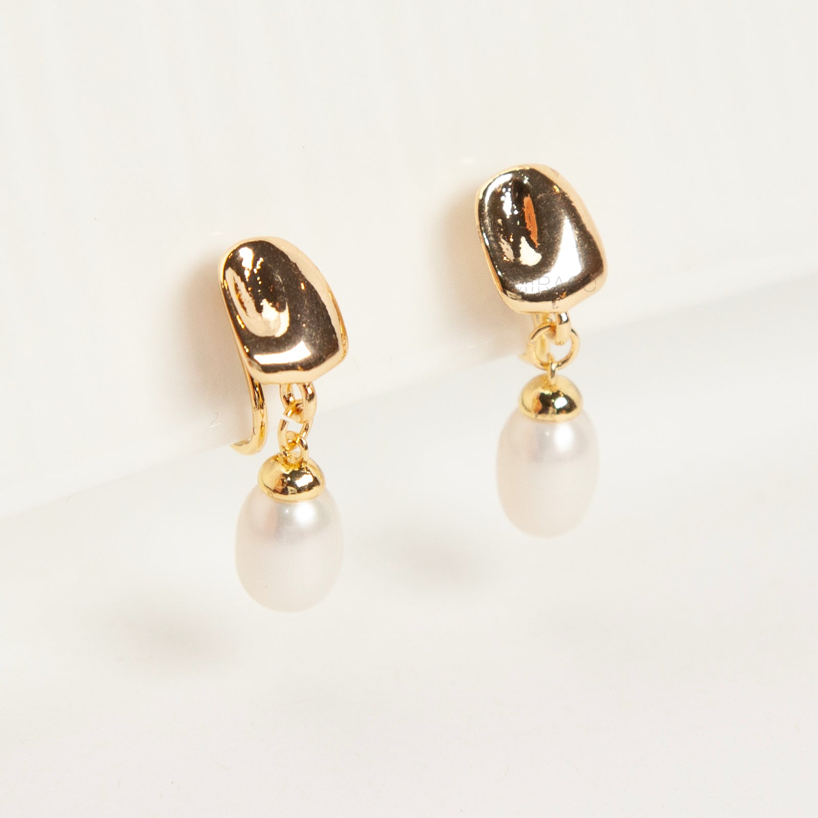 Pair of Gold-Tone Dangle Freshwater Pearl Clip-On Earrings with Coil Back closure.