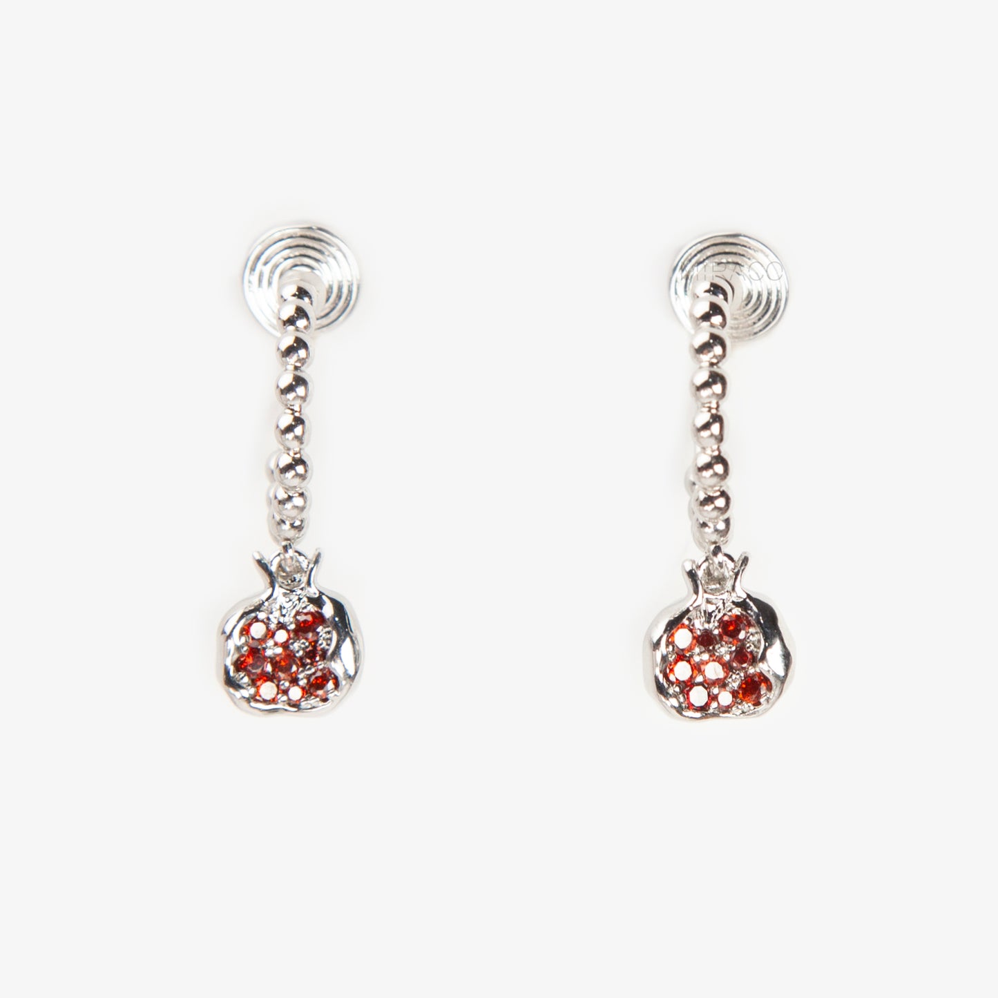Pair of silver-tone hoop clip-on earrings with a beaded design and a red CZ-encrusted pomegranate charm dangle. Shows the Coil Back mechanism.