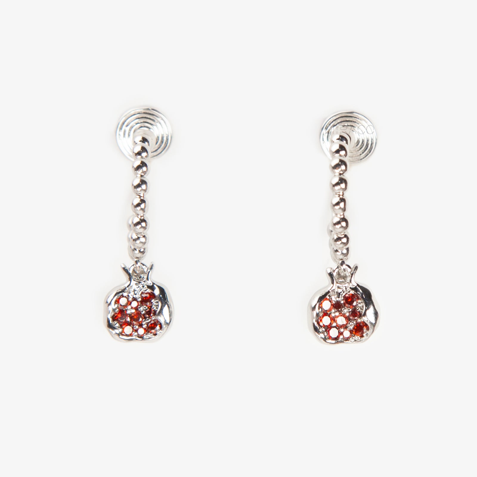 Pair of silver-tone hoop clip-on earrings with a beaded design and a red CZ-encrusted pomegranate charm dangle. Shows the Coil Back mechanism.
