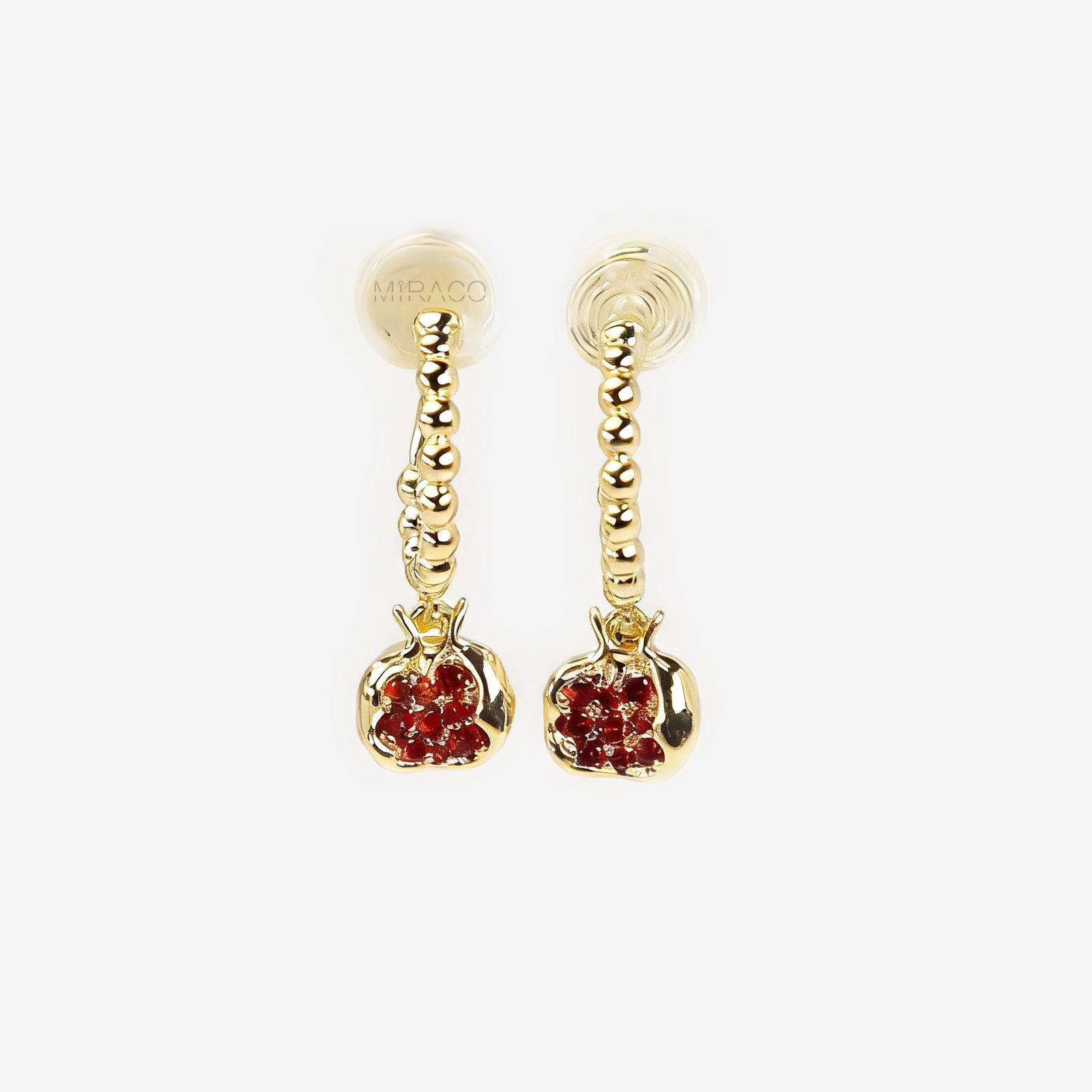 A pair of gold-tone clip-on earrings featuring a beaded drop design with a pomegranate charm filled with ruby red crystals, shown with comfortable coil backs.