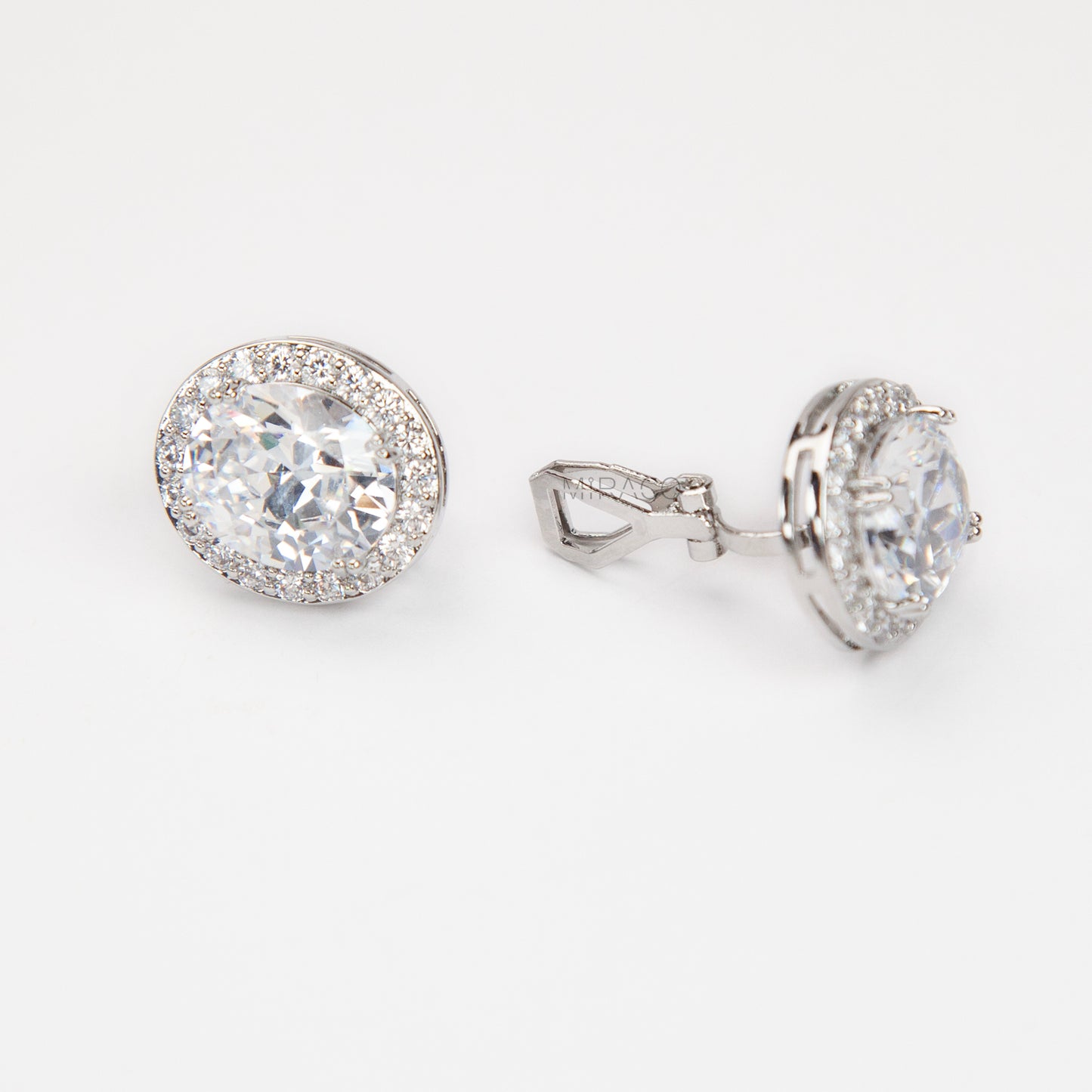 Pair of silver-tone oval halo clip-on stud earrings featuring a large central brilliant-cut cubic zirconia stone surrounded by a circle of small pave-set crystals.