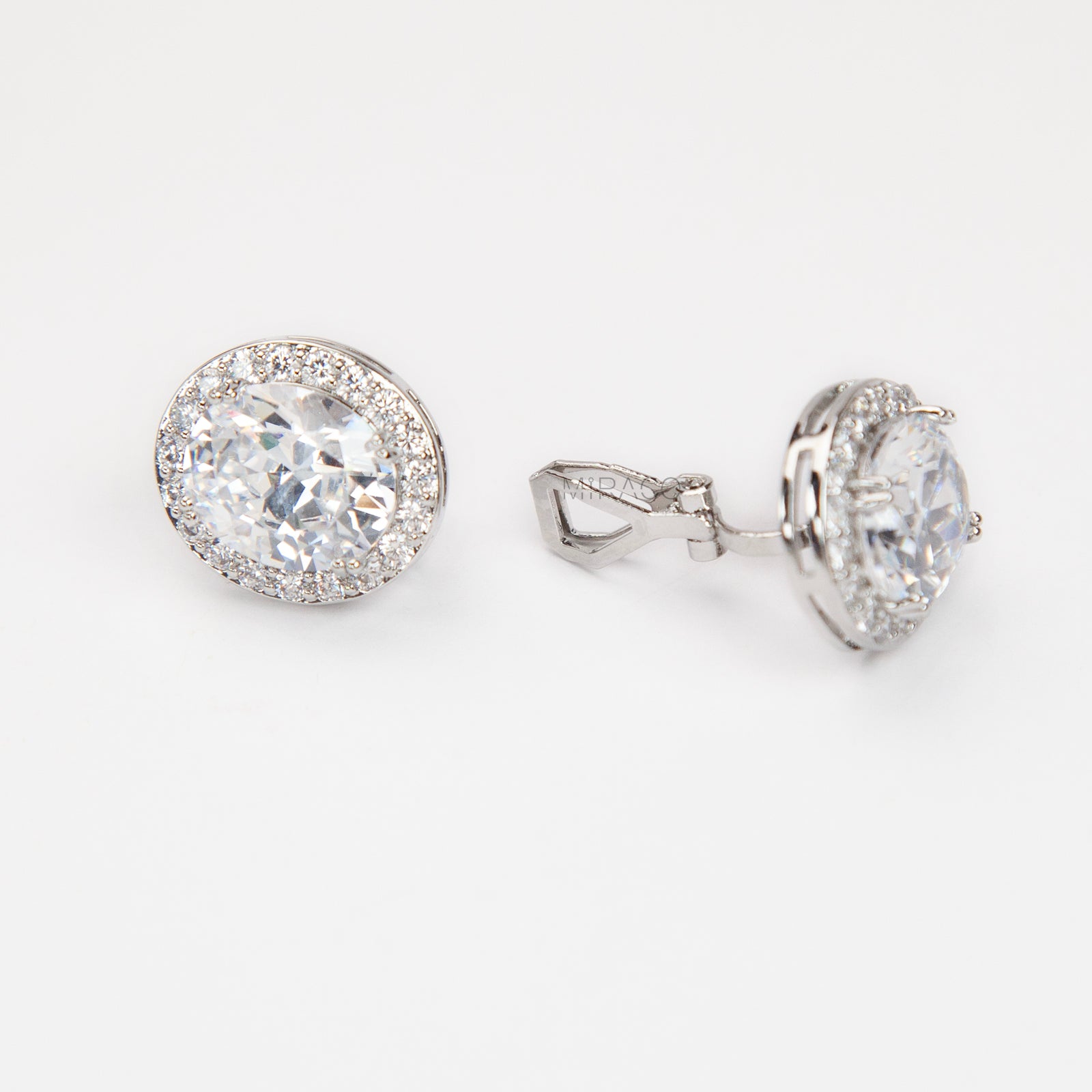 Pair of silver-tone oval halo clip-on stud earrings featuring a large central brilliant-cut cubic zirconia stone surrounded by a circle of small pave-set crystals.