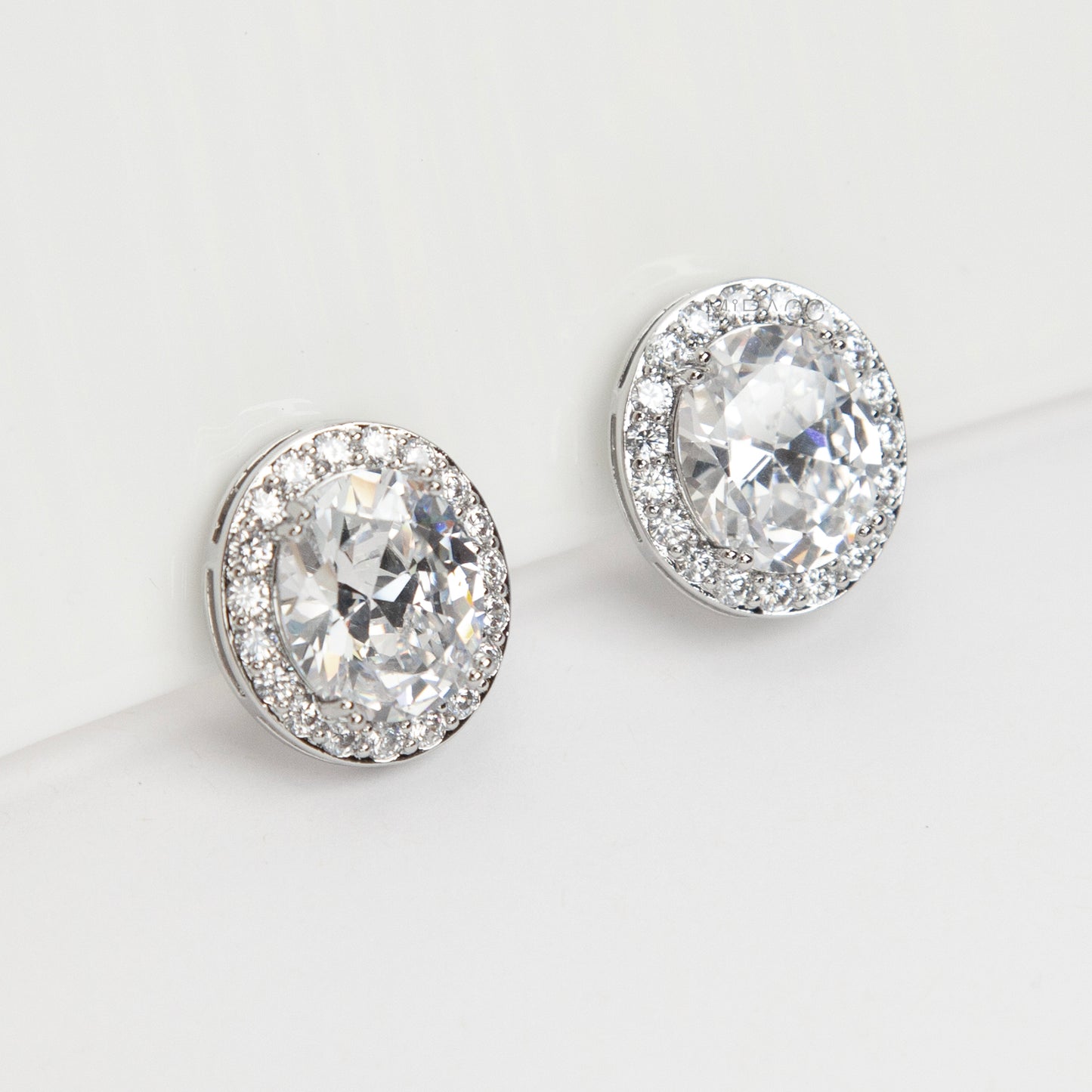 Pair of silver-tone oval halo clip-on stud earrings featuring a large central brilliant-cut cubic zirconia stone surrounded by a circle of small pave-set crystals.