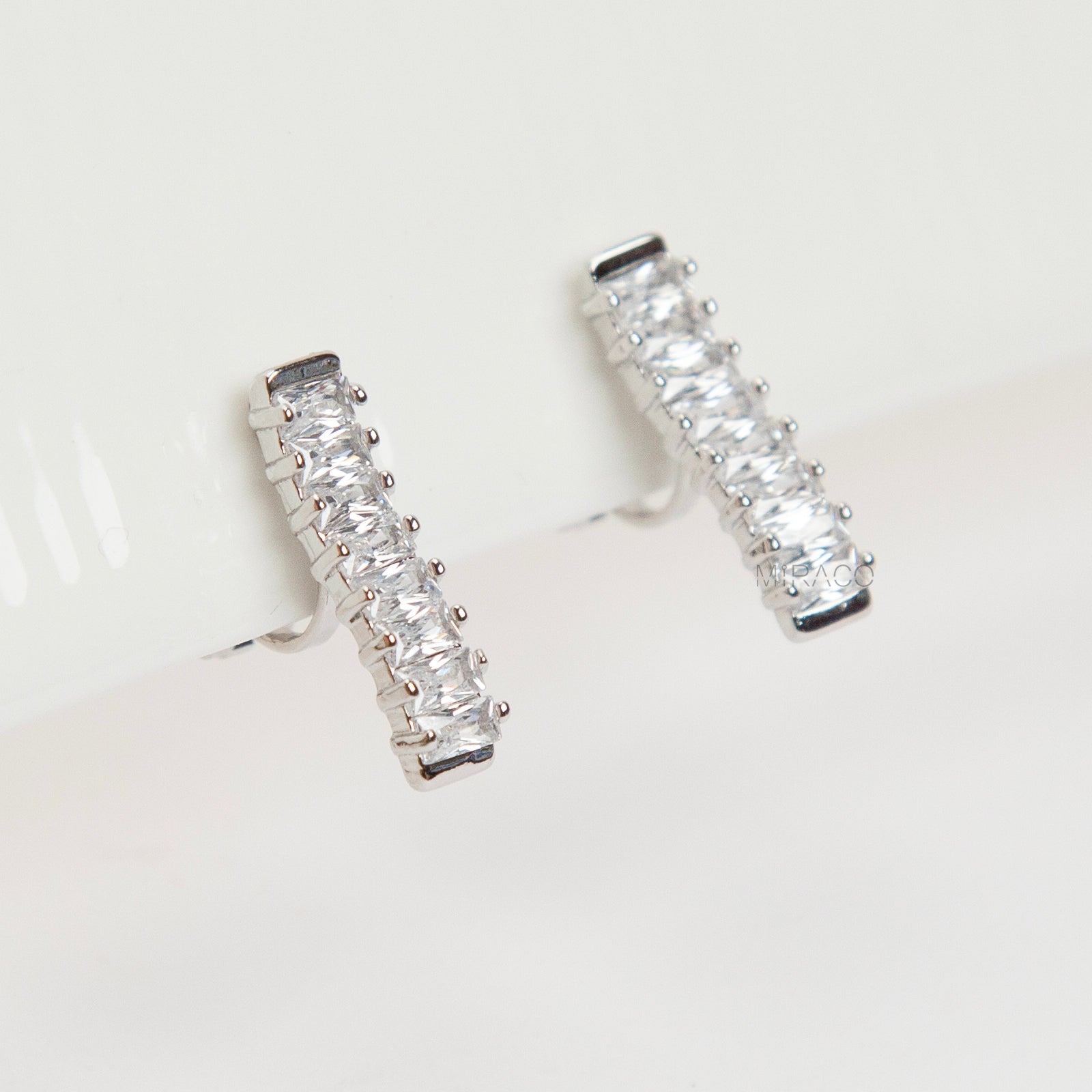 Pair of silver-tone vertical bar clip-on earrings featuring a column of rectangular baguette-cut cubic zirconia stones.