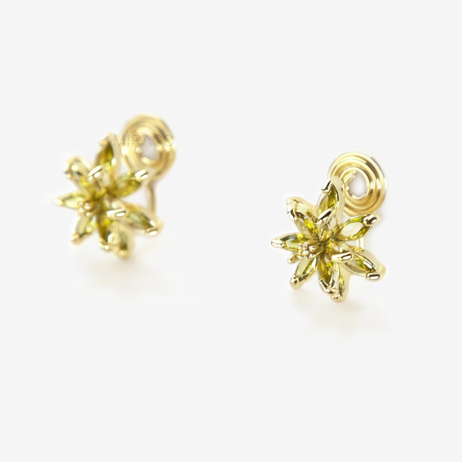 Pair of gold-tone clip-on earrings shaped like a flower or starburst, featuring marquise-cut peridot green crystals radiating from the center.