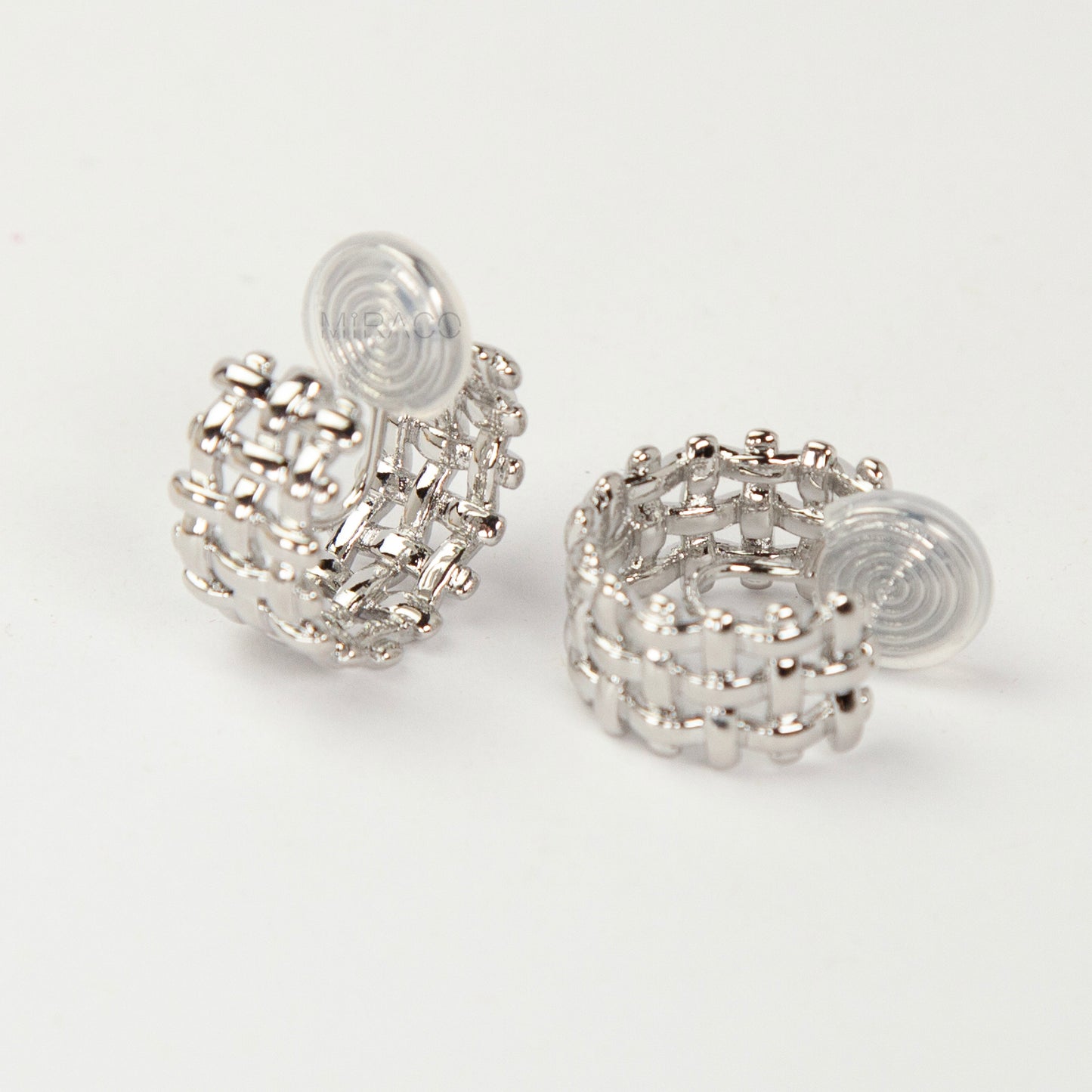 woven mesh coil back clip-on earrings on white background. Two are in silver tone and two are in gold tone. Shows the basketweave texture and the clear coil-back mechanism.