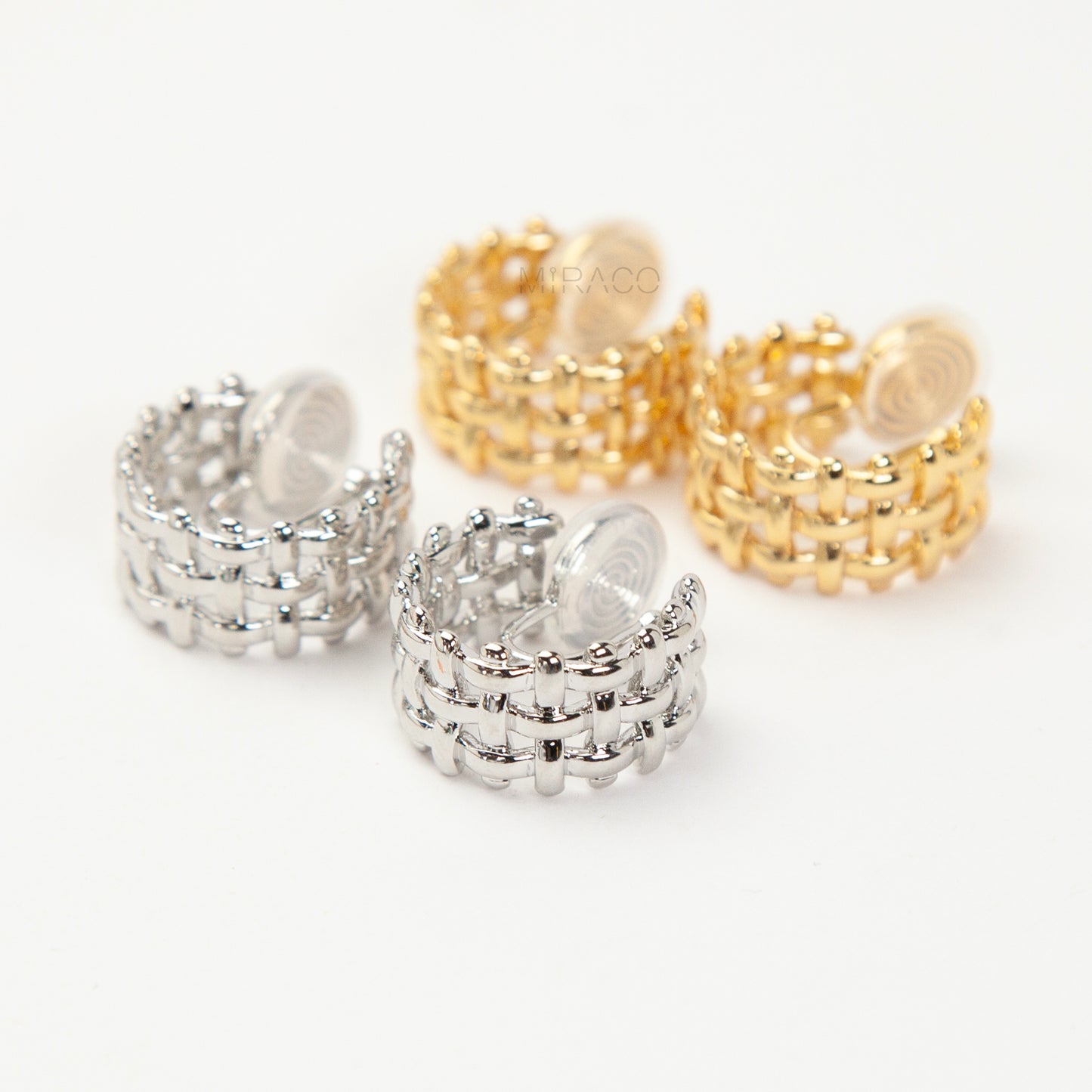 woven mesh coil back clip-on earrings on white background. Two are in silver tone and two are in gold tone. Shows the basketweave texture and the clear coil-back mechanism.