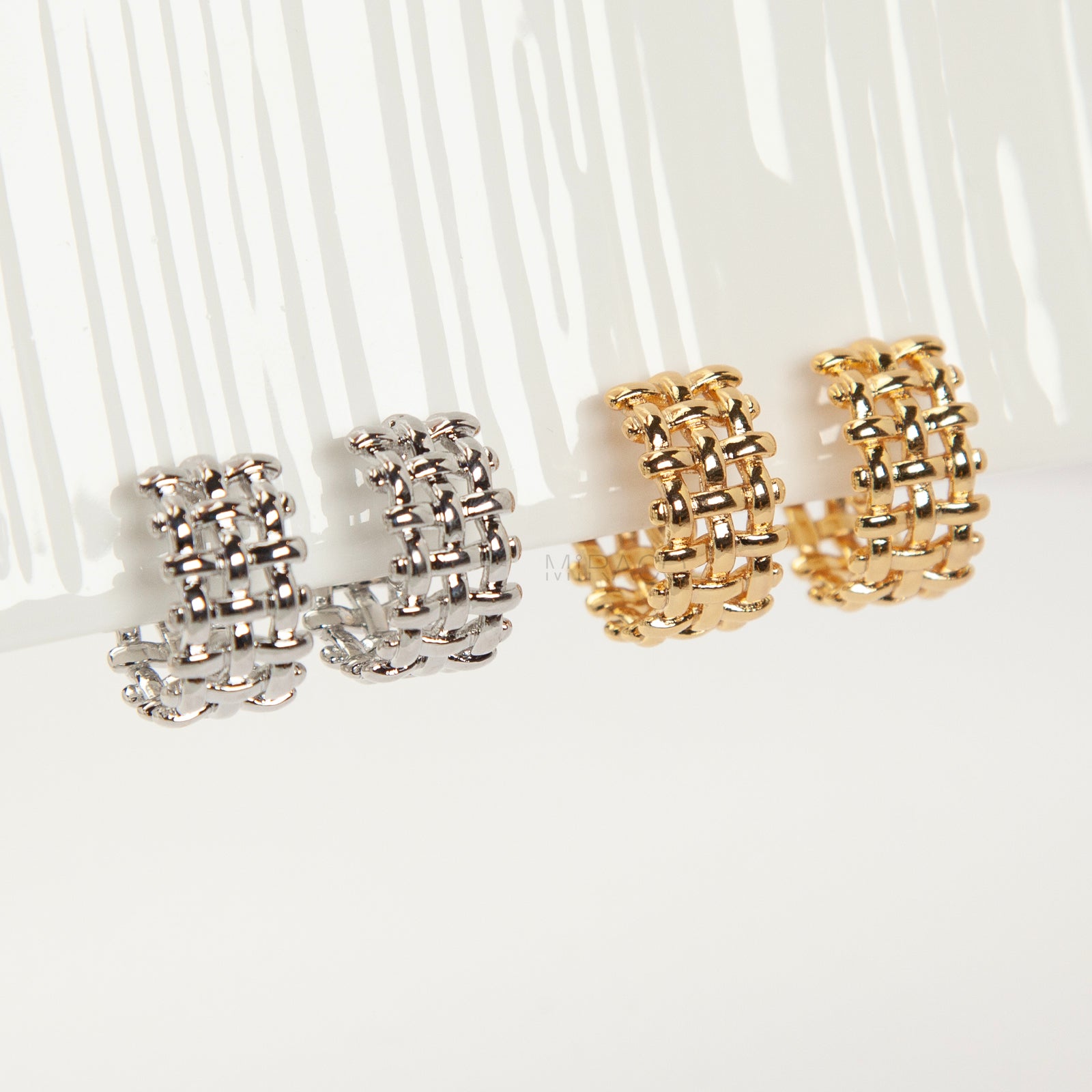 woven mesh coil back clip-on earrings on white background. Two are in silver tone and two are in gold tone. Shows the basketweave texture and the clear coil-back mechanism.