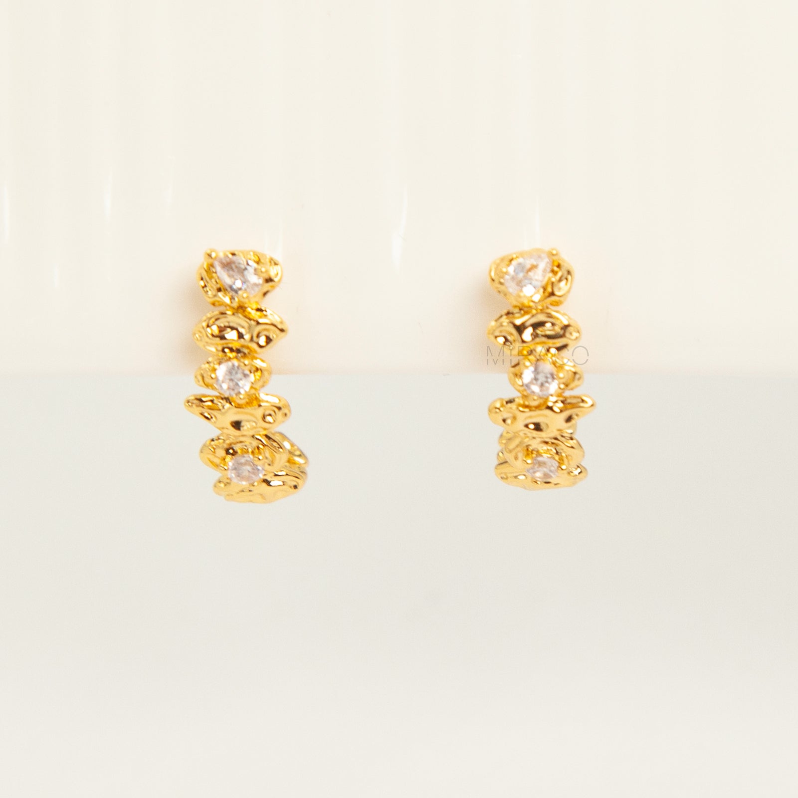 Gold-tone dangle clip-on earrings featuring stacked clear stones and a secure coil-back closure.