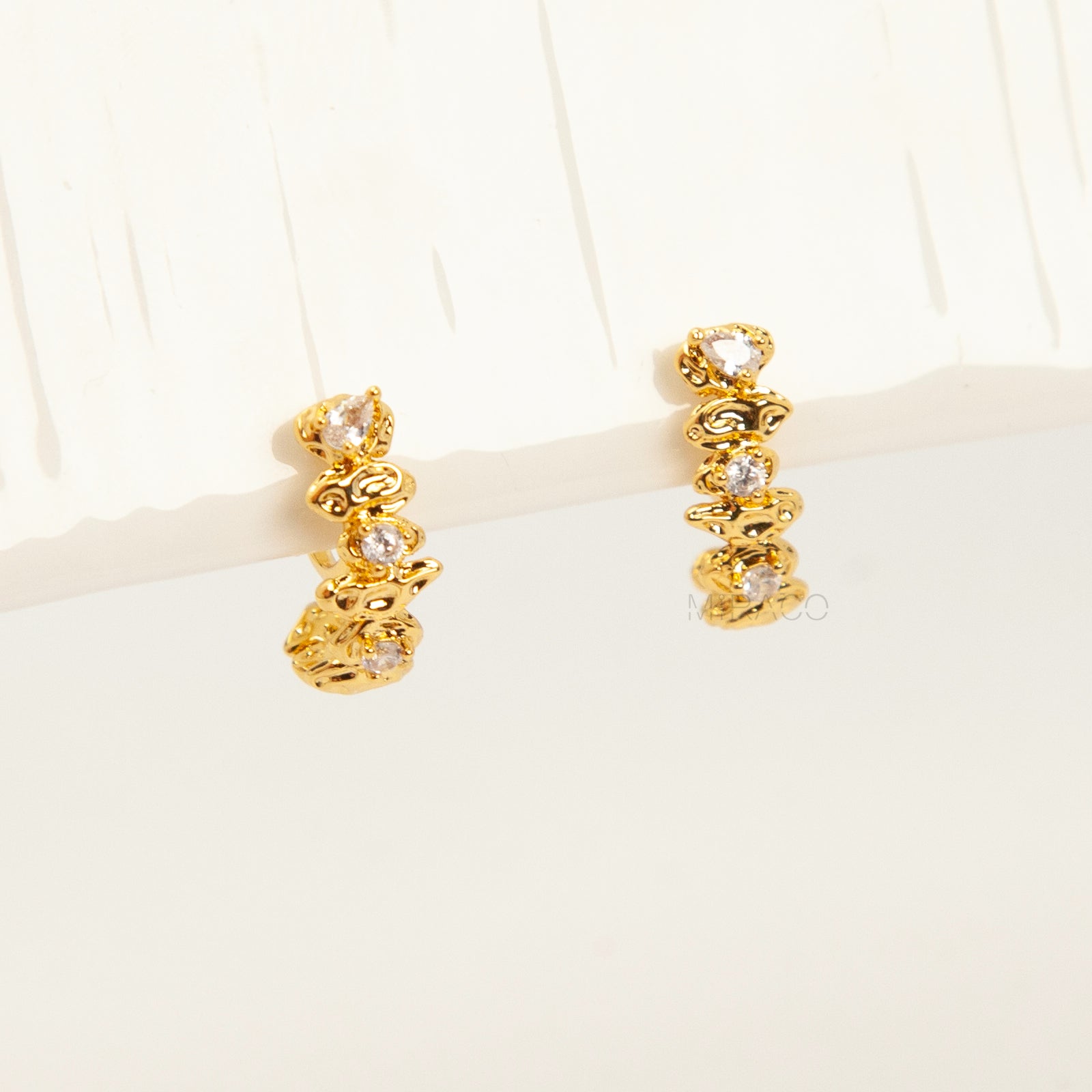 Gold-tone dangle clip-on earrings featuring stacked clear stones and a secure coil-back closure.