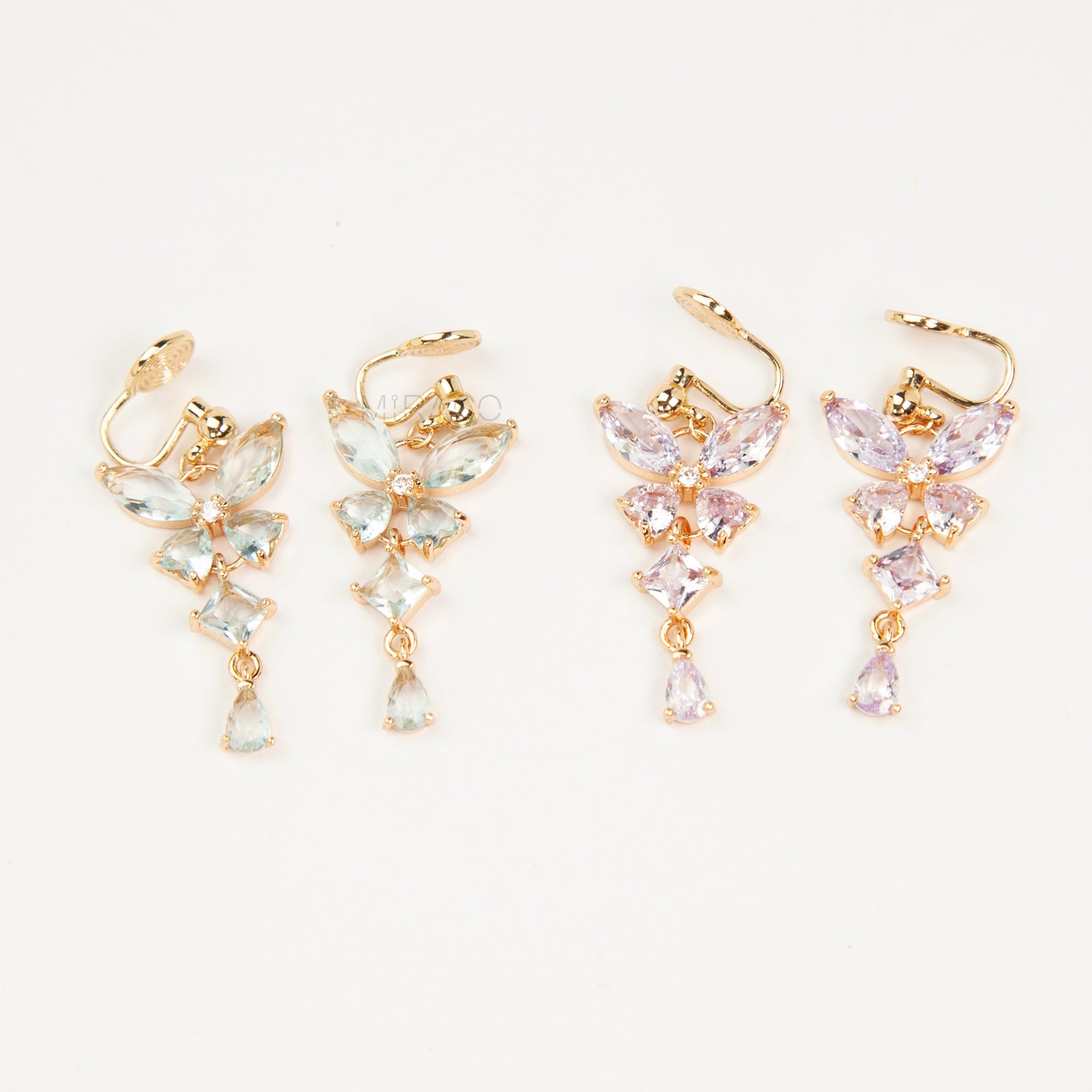 A pair of gold-tone, coil-back clip-on dangle earrings featuring a butterfly cluster of multifaceted Serene Aquamarine (pale blue) crystals and cascading drop stones.