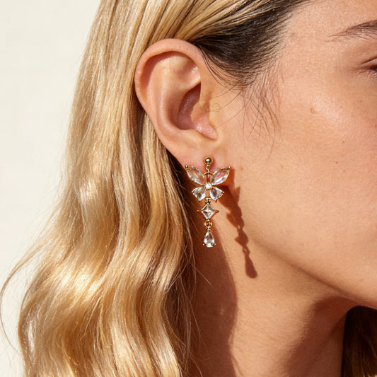 A pair of gold-tone, coil-back clip-on dangle earrings featuring a butterfly cluster of multifaceted Serene Aquamarine (pale blue) crystals and cascading drop stones.