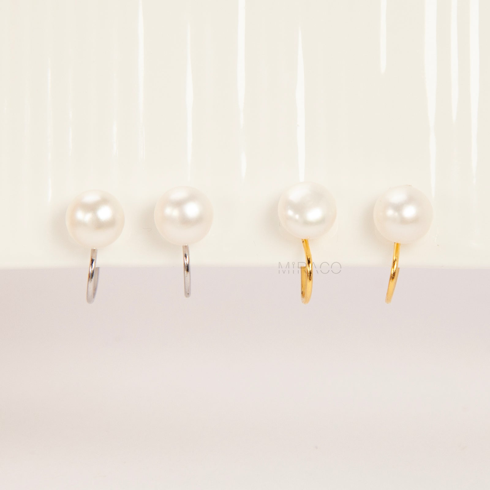 round freshwater pearl clip-on earrings with clear silicone comfort backs, shown in both gold-plated and silver-plated finishes on a white background.