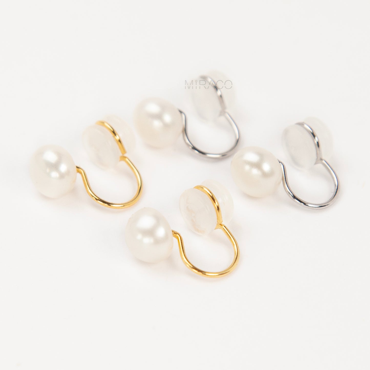 round freshwater pearl clip-on earrings with clear silicone comfort backs, shown in both gold-plated and silver-plated finishes on a white background.