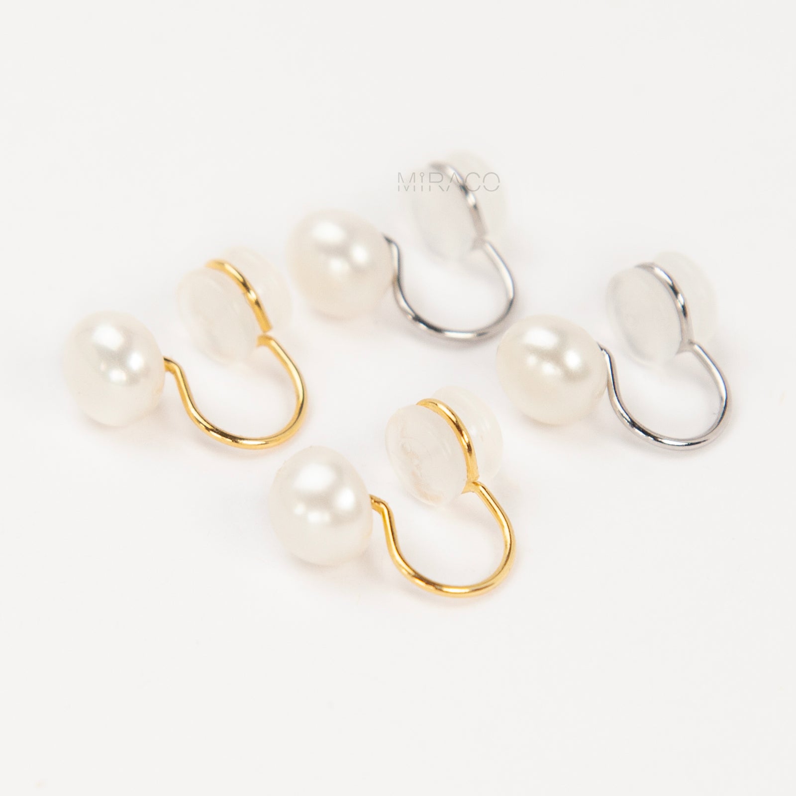 round freshwater pearl clip-on earrings with clear silicone comfort backs, shown in both gold-plated and silver-plated finishes on a white background.