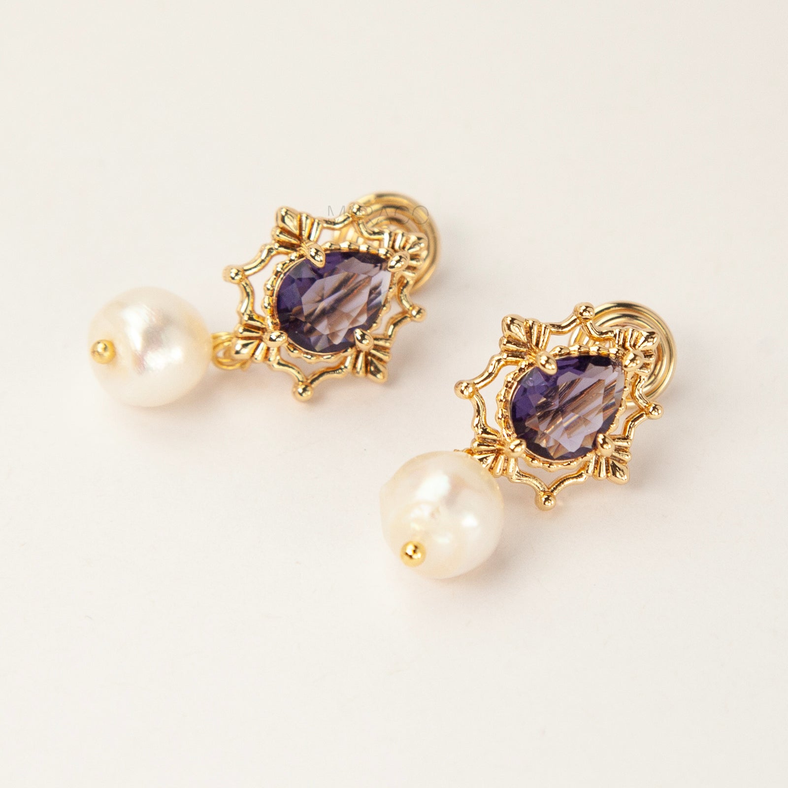Pair of gold-plated, coil-back clip-on earrings with an ornate Victorian-style setting holding a purple pear-cut gemstone (amethyst color) and a dangling real baroque freshwater pearl.