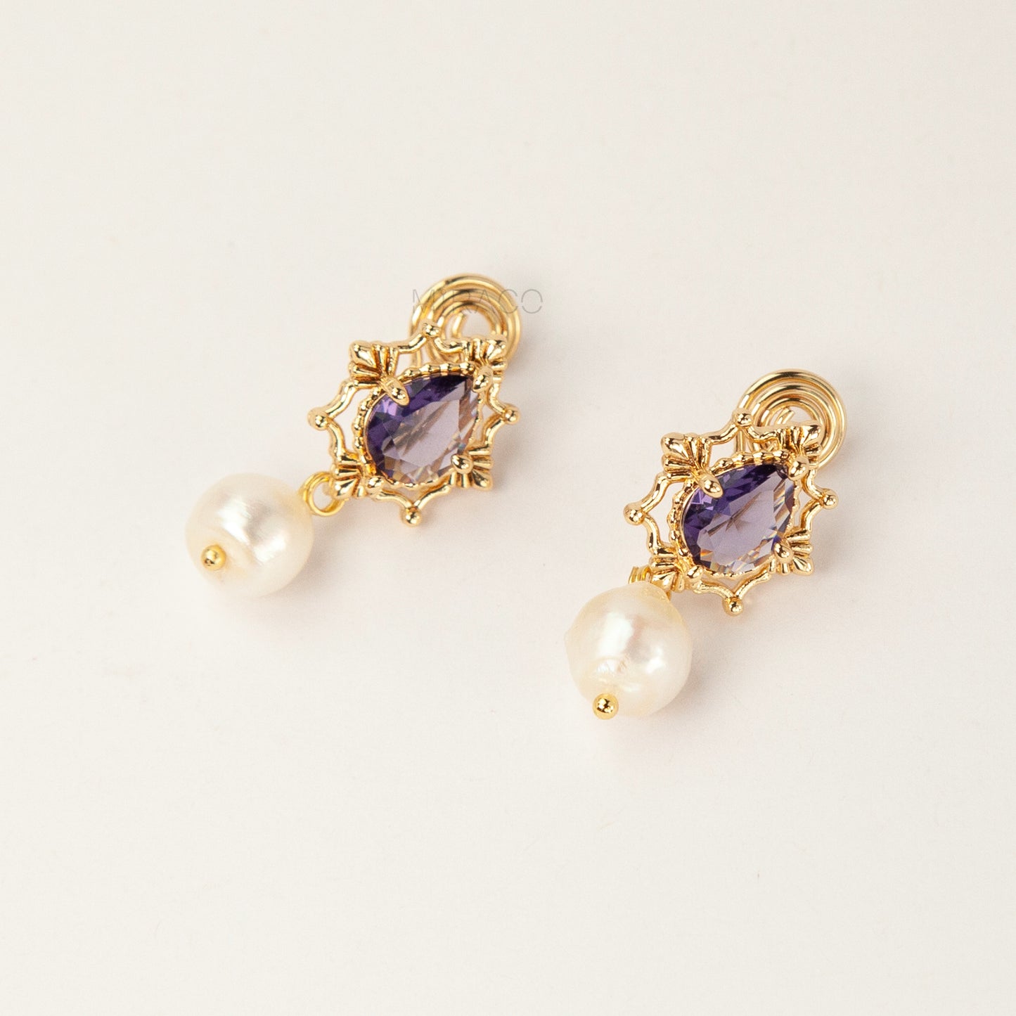 Pair of gold-plated, coil-back clip-on earrings with an ornate Victorian-style setting holding a purple pear-cut gemstone (amethyst color) and a dangling real baroque freshwater pearl.