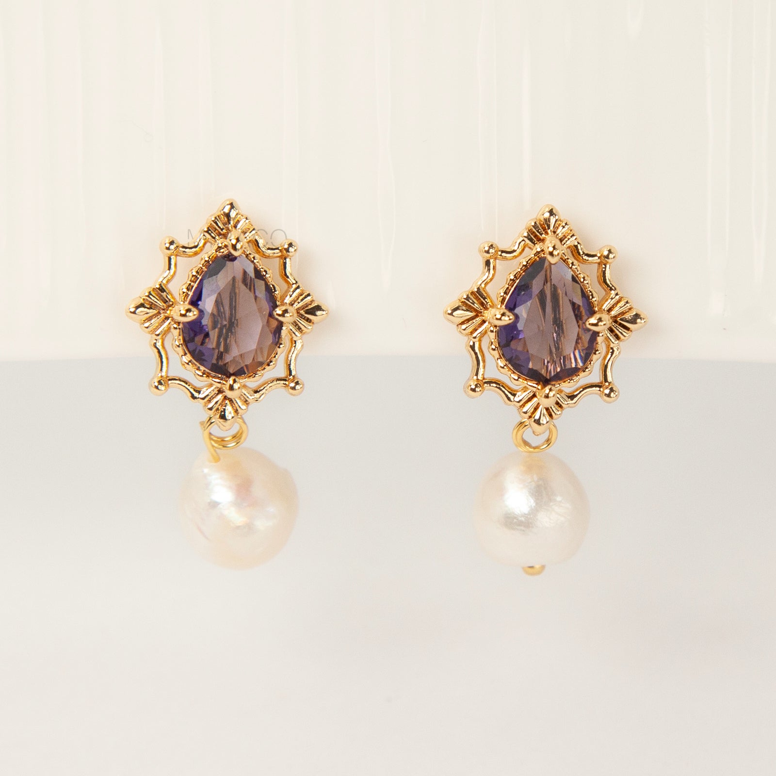 Pair of gold-plated, coil-back clip-on earrings with an ornate Victorian-style setting holding a purple pear-cut gemstone (amethyst color) and a dangling real baroque freshwater pearl.