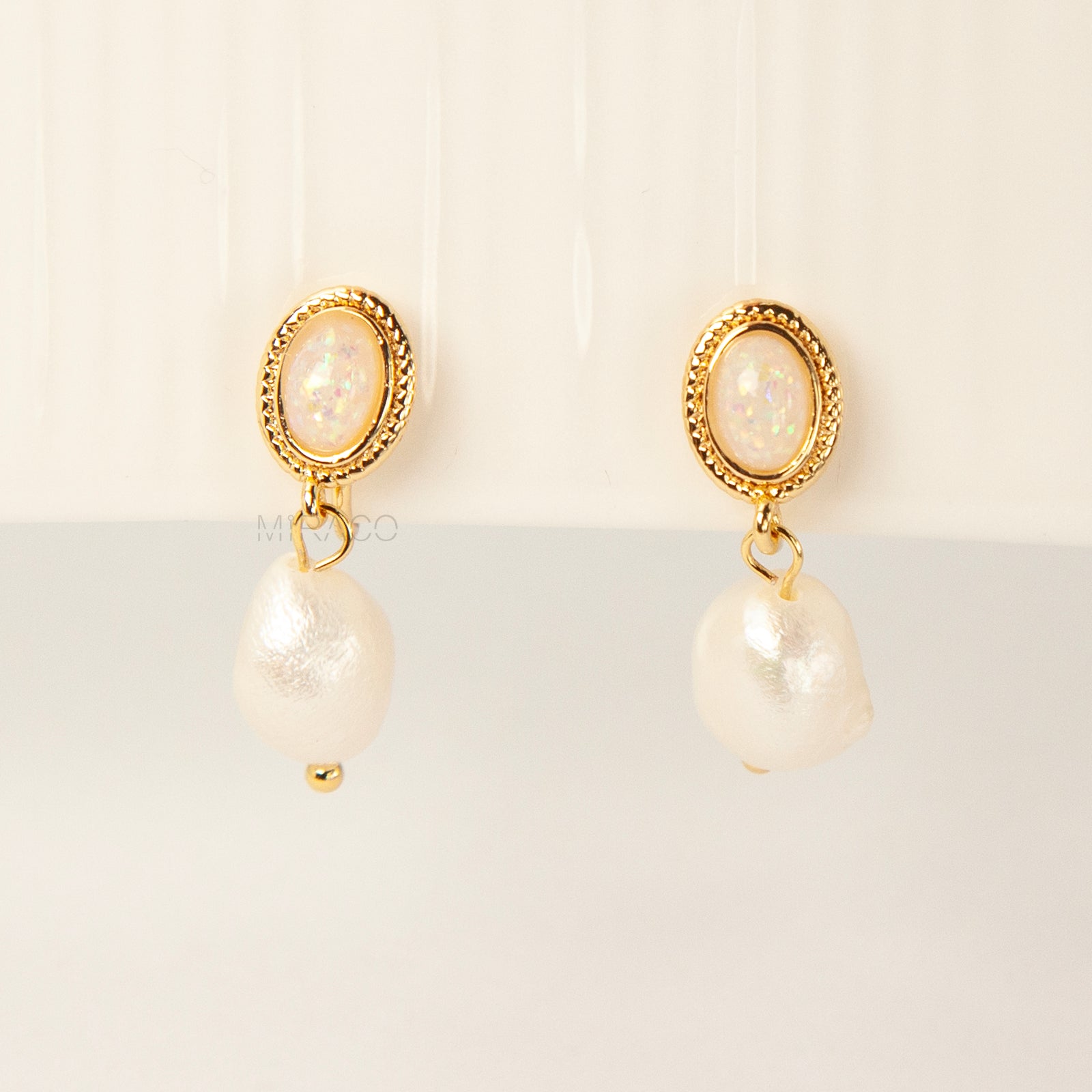 Pair of gold-tone, coil-back clip-on earrings with an oval, bezel-set iridescent opal-effect stone and a dangling real, irregularly shaped baroque freshwater pearl.