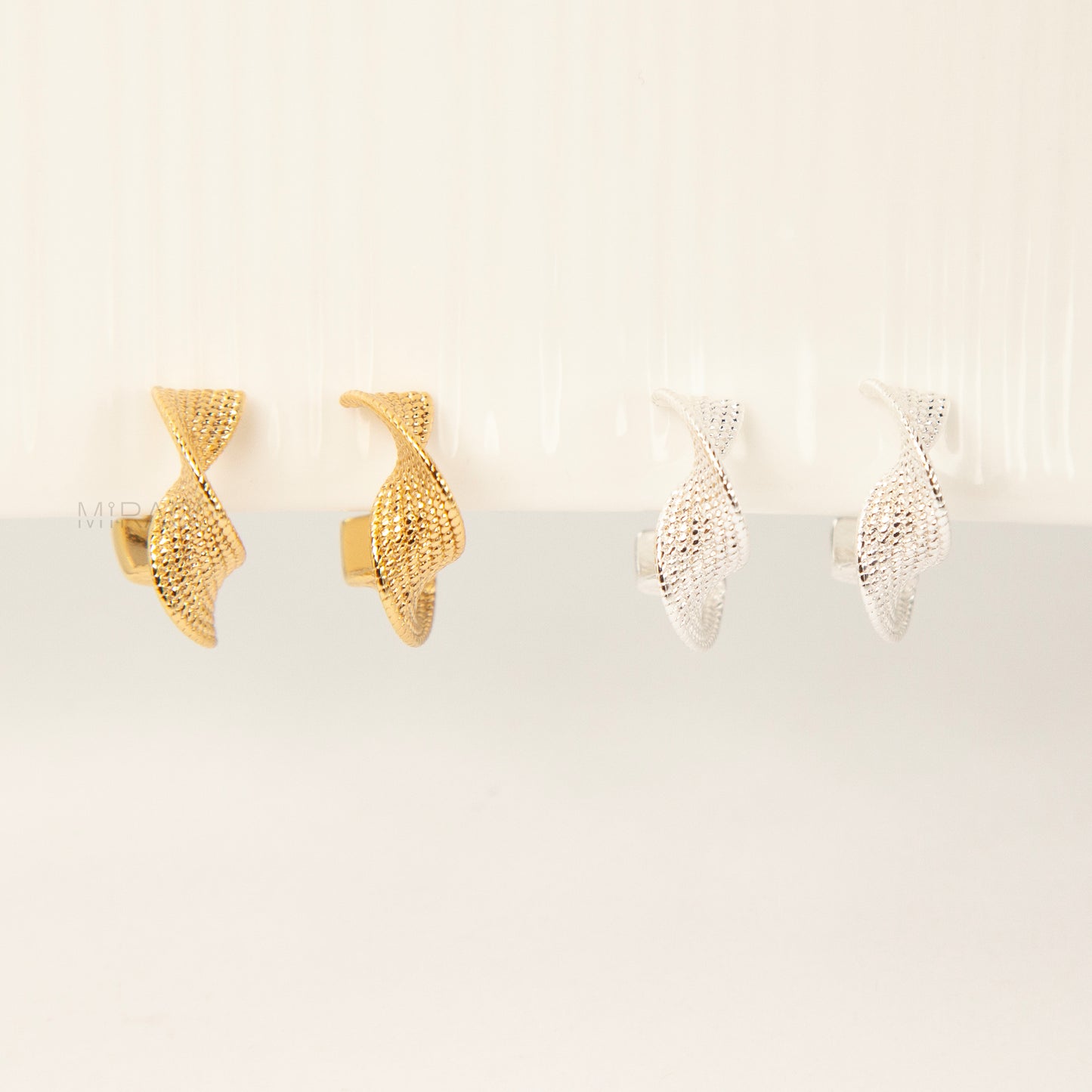 two pairs of small, twisted texture clip-on hoop earrings with a coil/screw back, one pair in gold tone and one in silver tone 