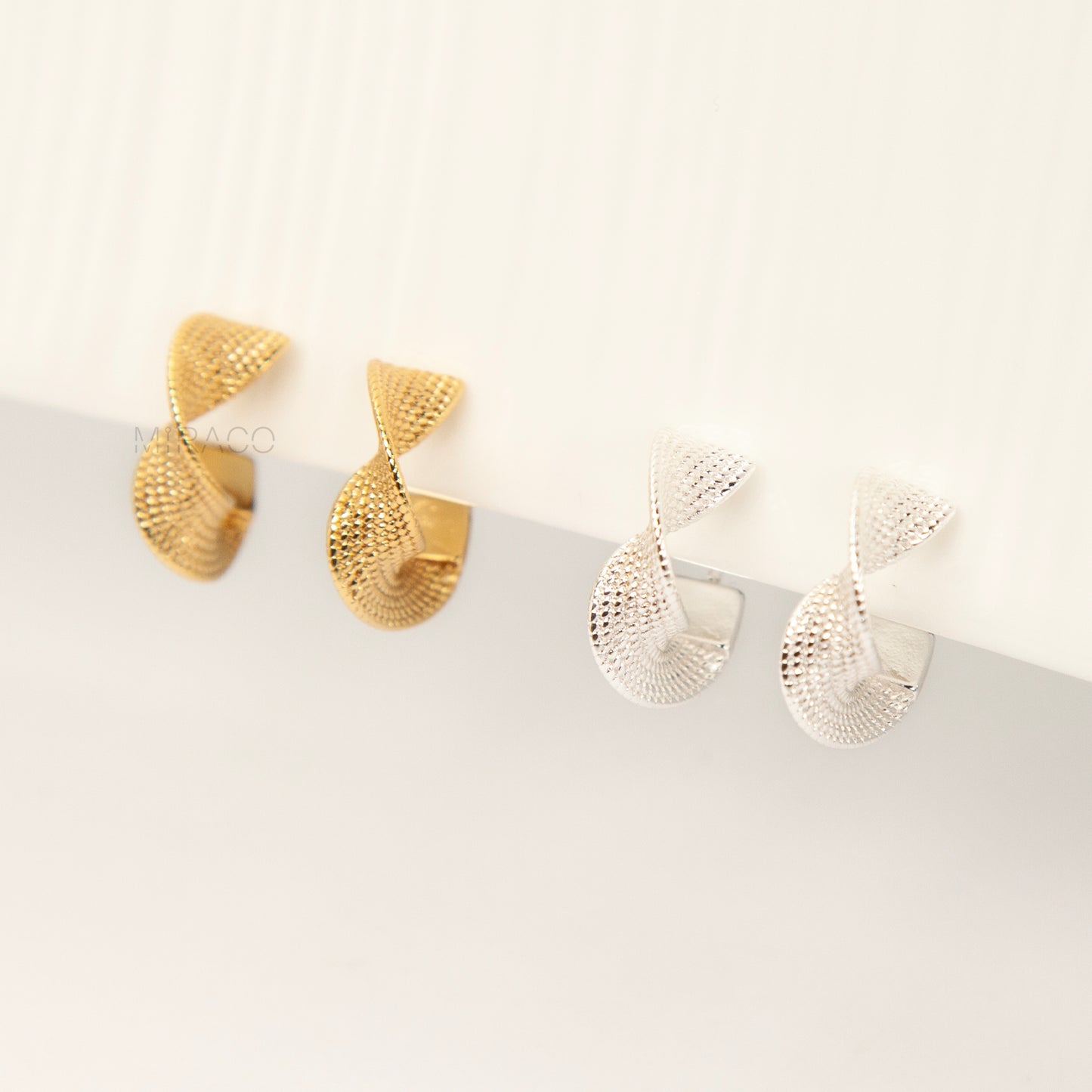 two pairs of small, twisted texture clip-on hoop earrings with a coil/screw back, one pair in gold tone and one in silver tone 