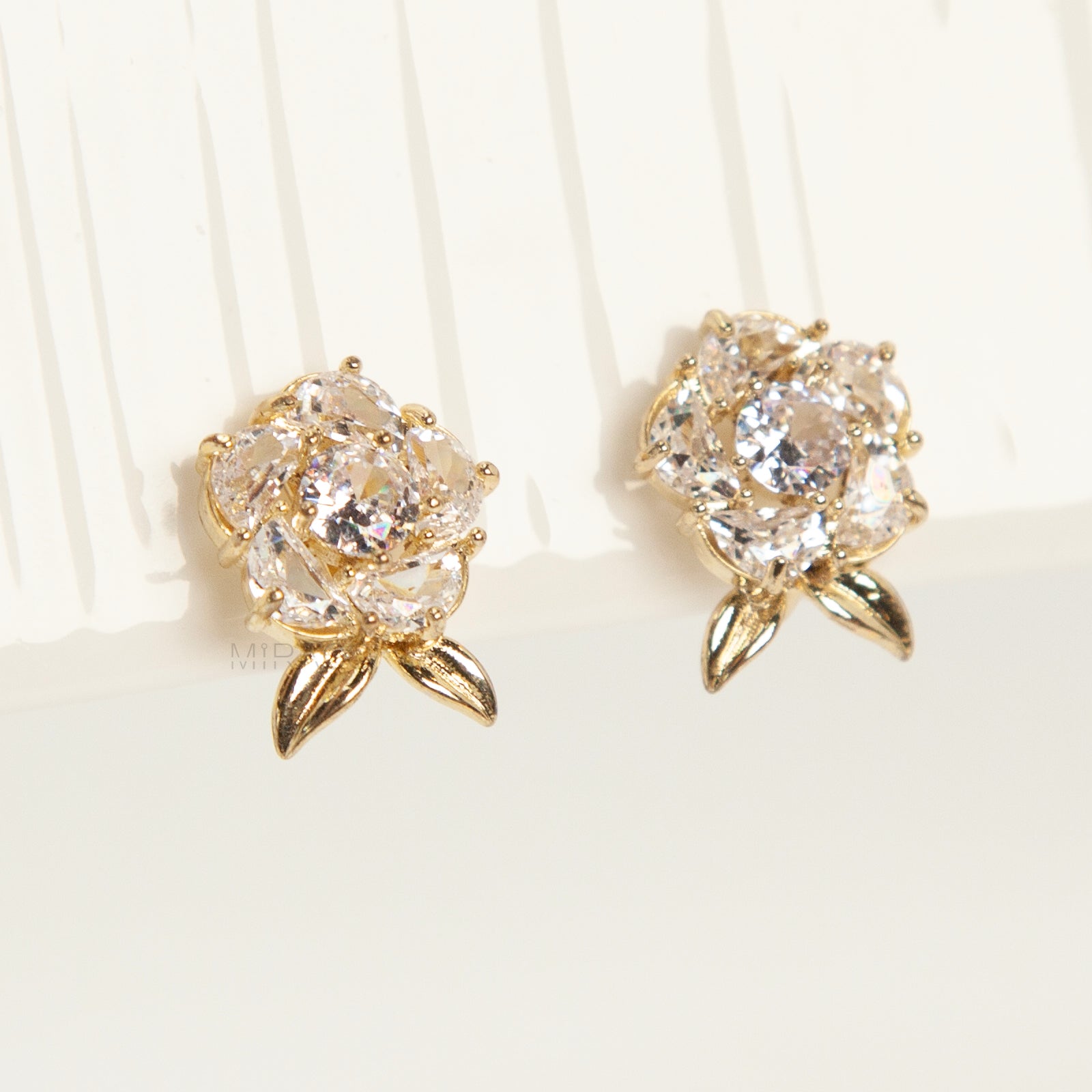 Pair of elegant gold-tone clip-on stud earrings shaped like a fully bloomed rose flower, set with a cluster of round and marquise-cut cubic zirconia stones, with a coil back clasp.