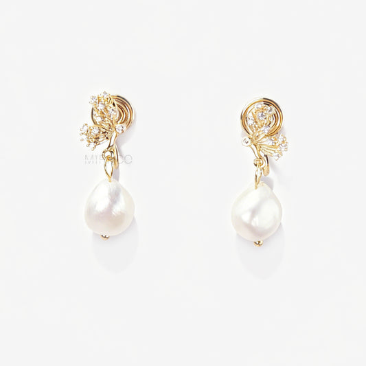 Pair of elegant gold-tone clip-on earrings with a CZ-encrusted butterfly swirl top and a dangling, lustrous white Baroque pearl drop, secured with a comfortable coil back clasp.