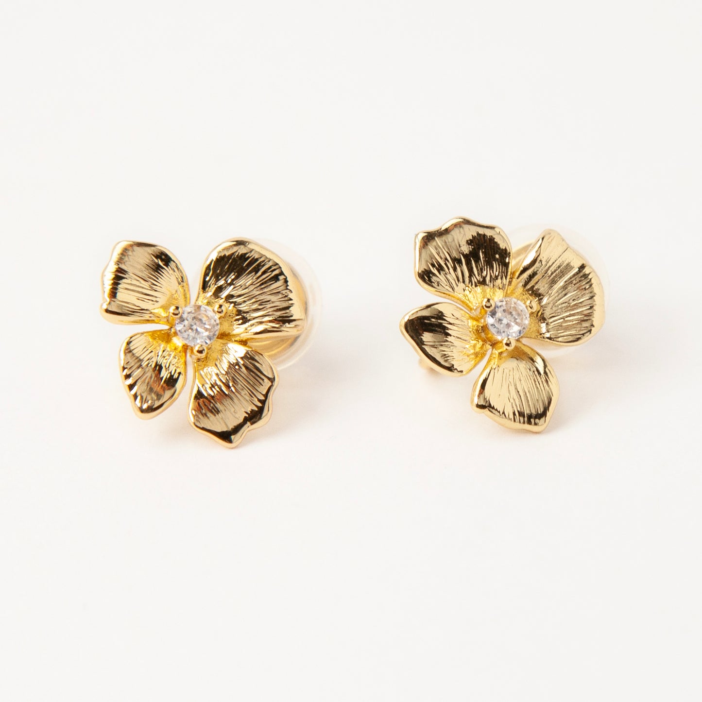 Pair of gold-tone textured flower-shaped clip-on earrings with a round clear crystal center and comfortable coil-back closures on a white background.