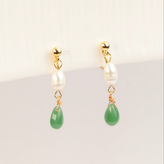 A pair of gold clip-on earrings featuring a comfortable coil back mechanism, a white oval pearl, and a dangling green jade teardrop stone.