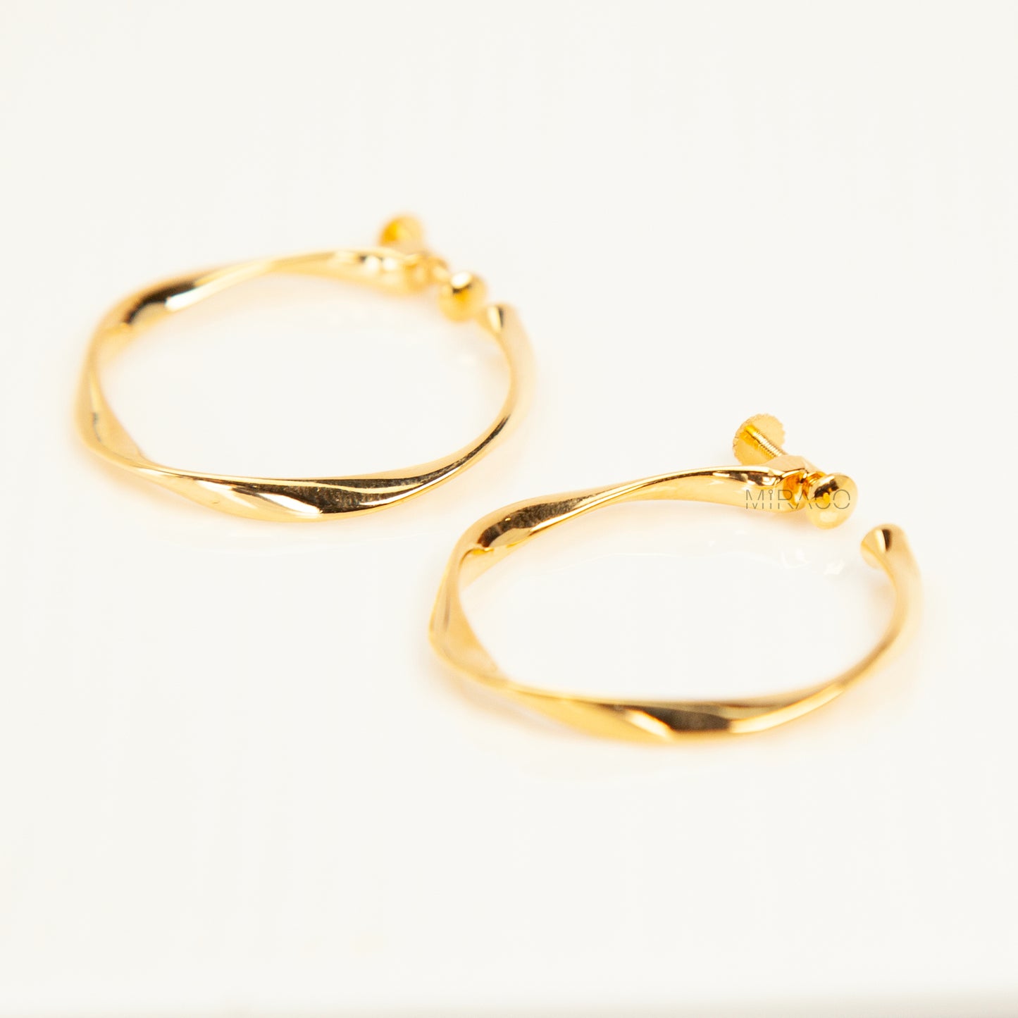 Pair of polished gold twisted hoop clip-on earrings with adjustable screw-back closures