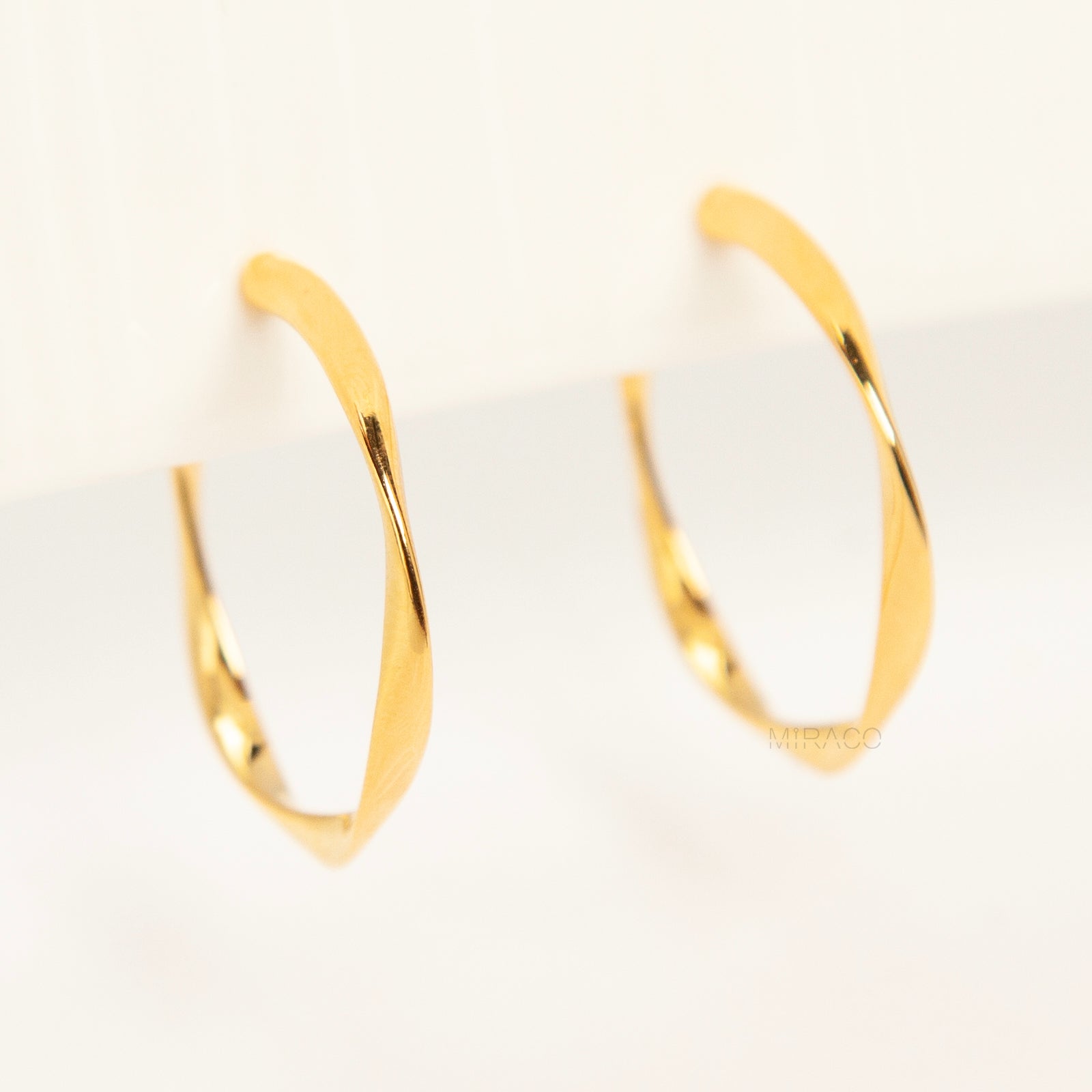 Pair of polished gold twisted hoop clip-on earrings with adjustable screw-back closures