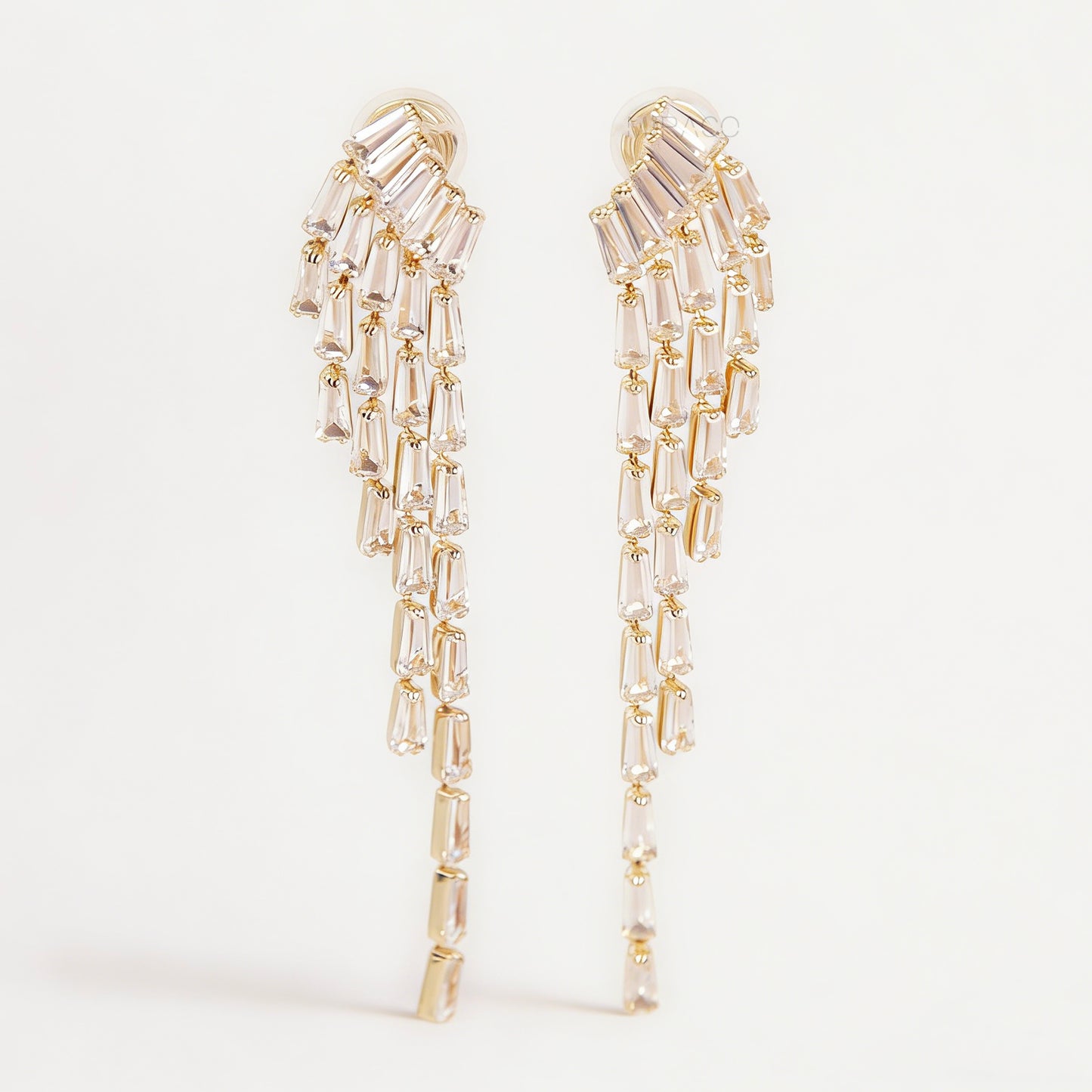 Pair of long gold-tone chandelier clip-on earrings featuring cascading baguette-cut crystals and a comfortable coil back fastening.