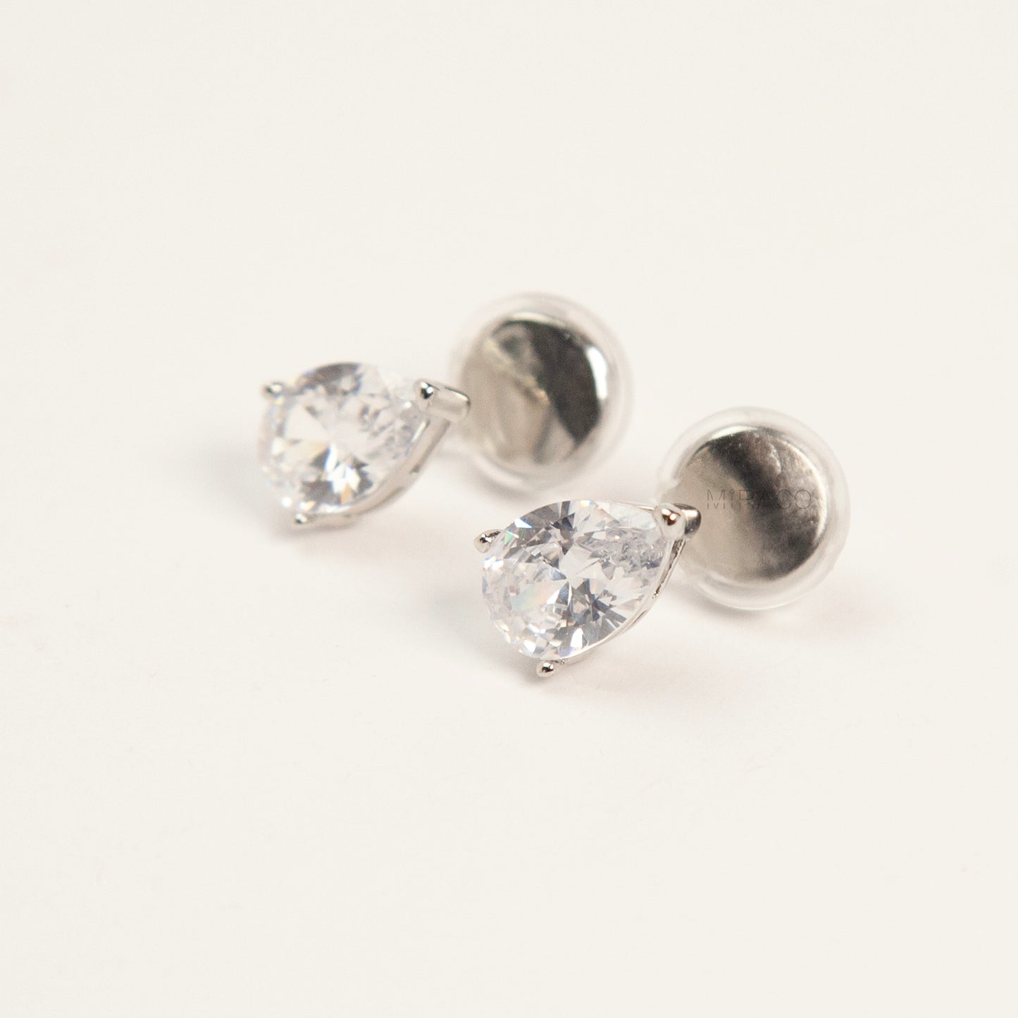 teardrop-shaped cubic zirconia clip-on earrings in gold and silver settings featuring invisible coil back closures.
