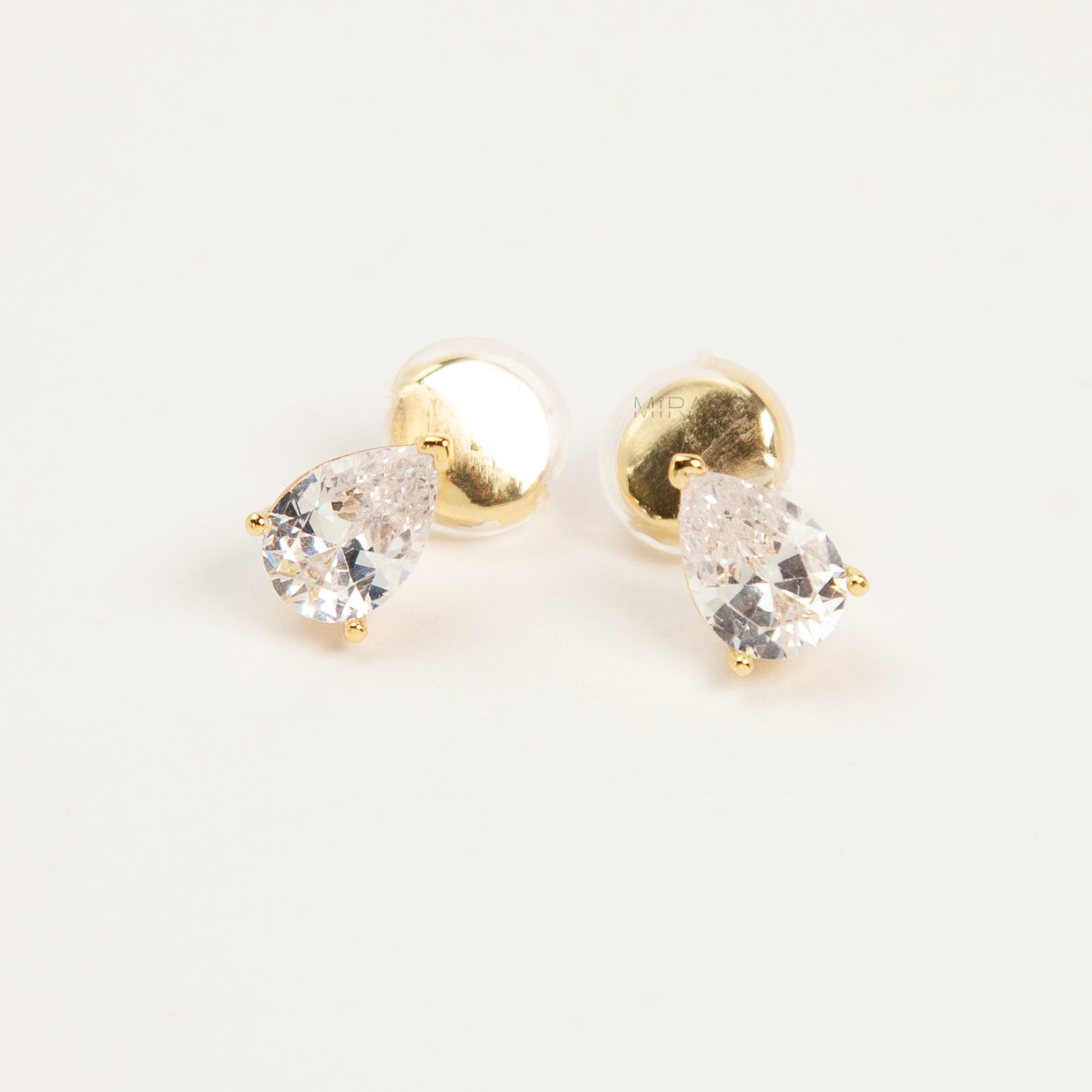 teardrop-shaped cubic zirconia clip-on earrings in gold and silver settings featuring invisible coil back closures.