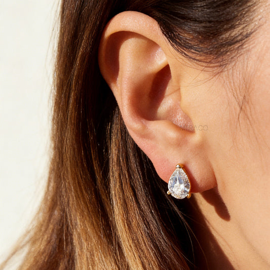 Two pairs of teardrop-shaped cubic zirconia clip-on earrings in gold and silver settings featuring invisible coil back closures.