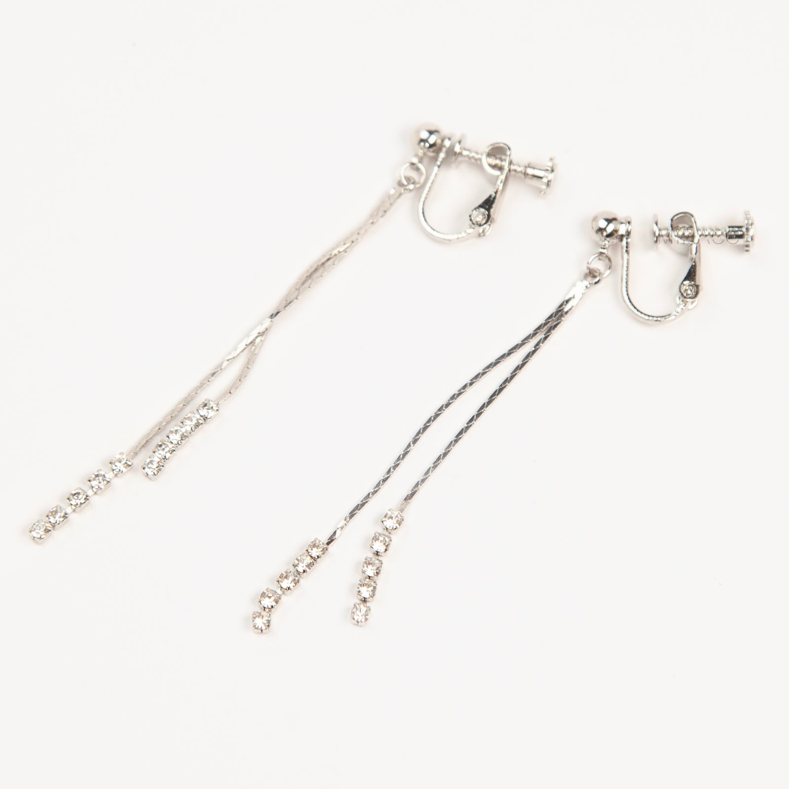 Pair of silver double-strand linear drop clip-on earrings with crystal tips and adjustable screw-back closures on a white background.