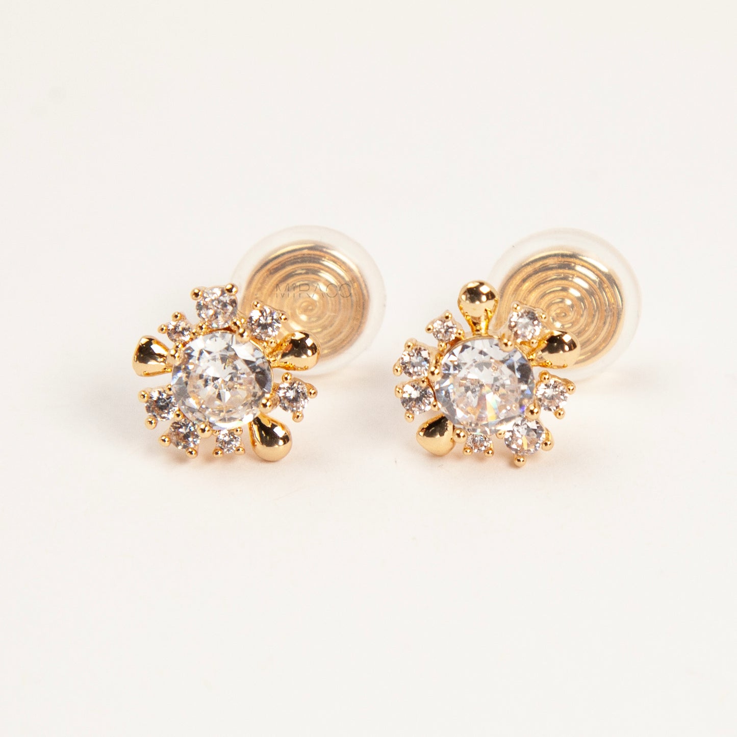 Pair of gold-tone sunburst-shaped clip-on earrings with a central cubic zirconia stone and comfortable invisible coil back closures.