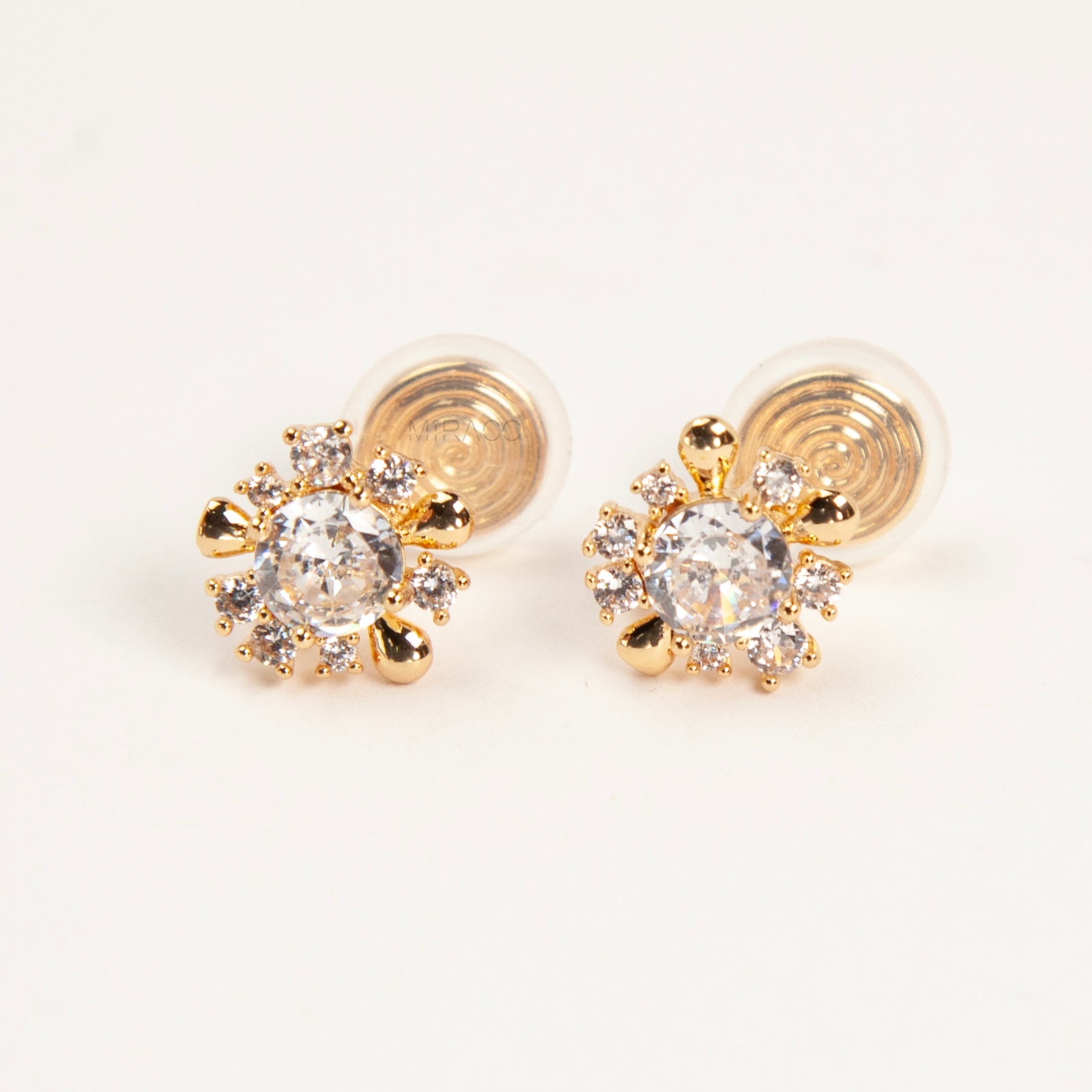 Pair of gold-tone sunburst-shaped clip-on earrings with a central cubic zirconia stone and comfortable invisible coil back closures.