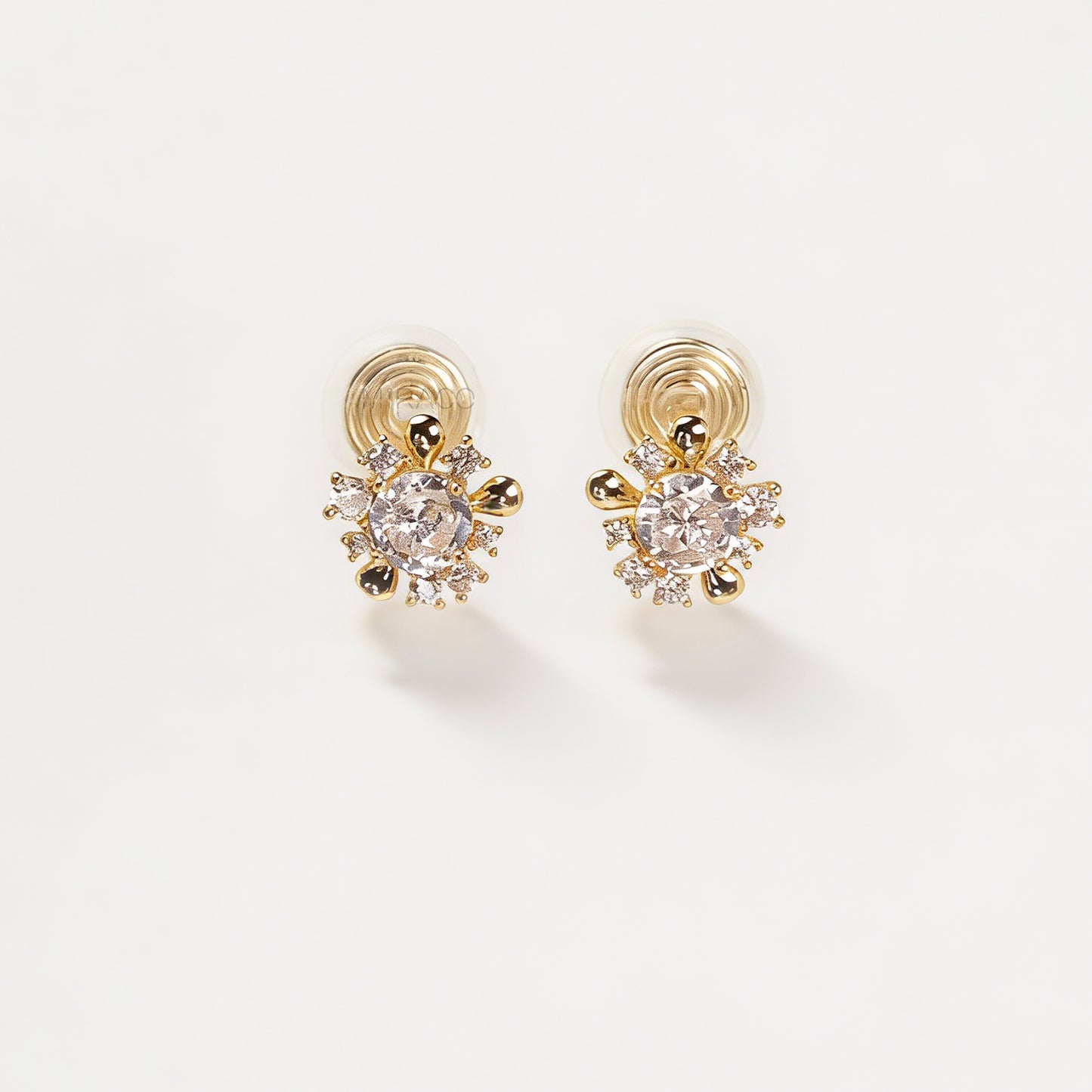 Pair of gold-tone sunburst-shaped clip-on earrings with a central cubic zirconia stone and comfortable invisible coil back closures.