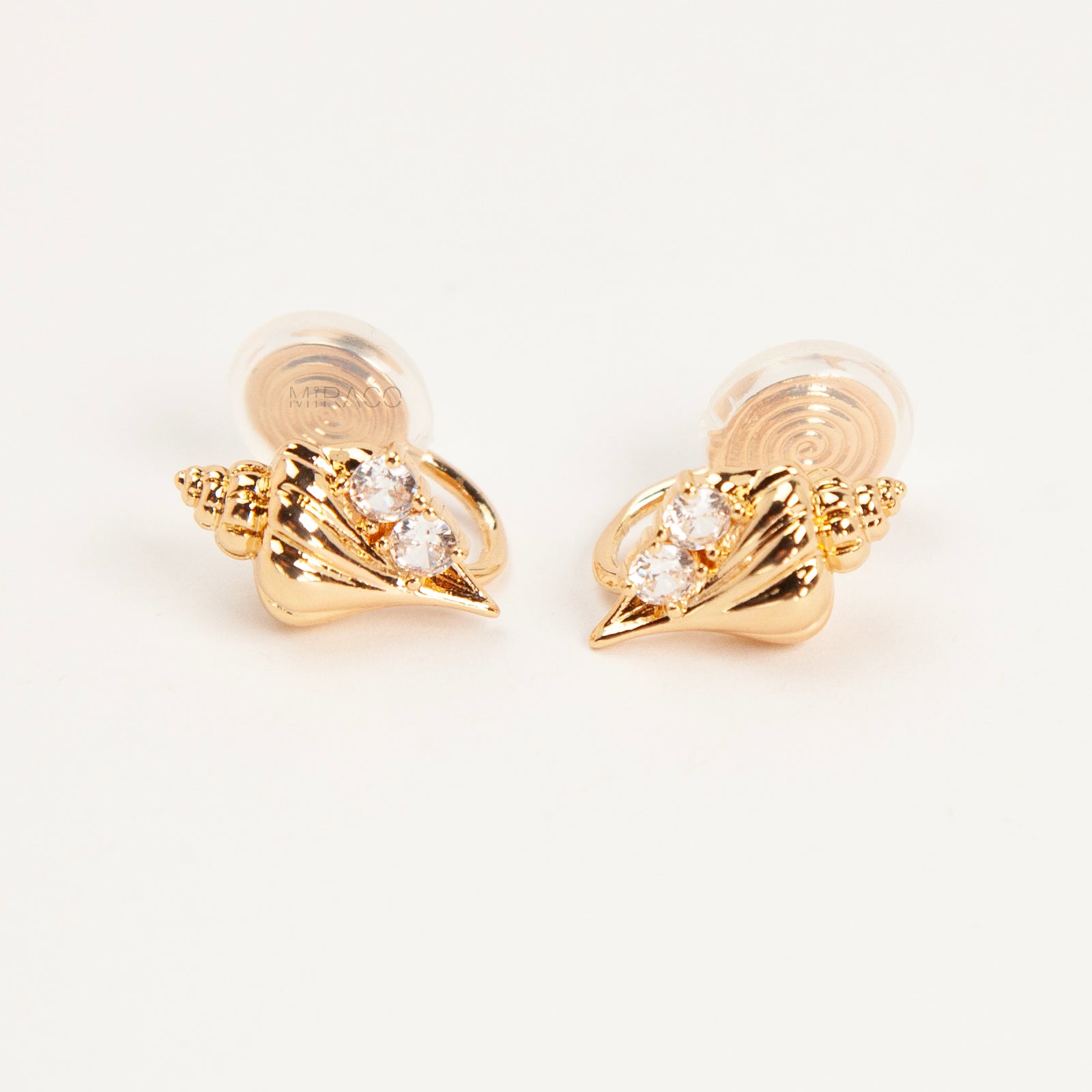Pair of small gold-tone conch seashell clip-on earrings accented with clear crystals and featuring comfortable invisible coil back closures.