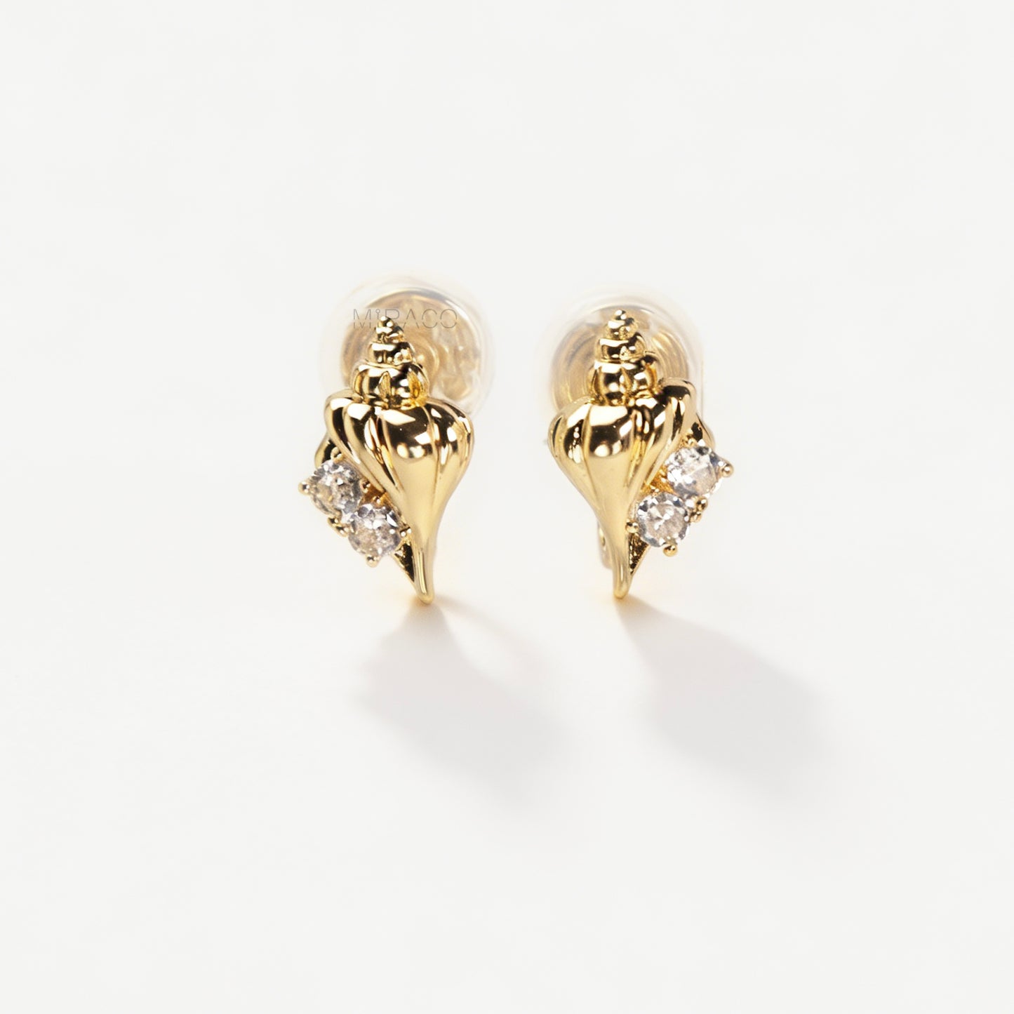 Pair of small gold-tone conch seashell clip-on earrings accented with clear crystals and featuring comfortable invisible coil back closures.