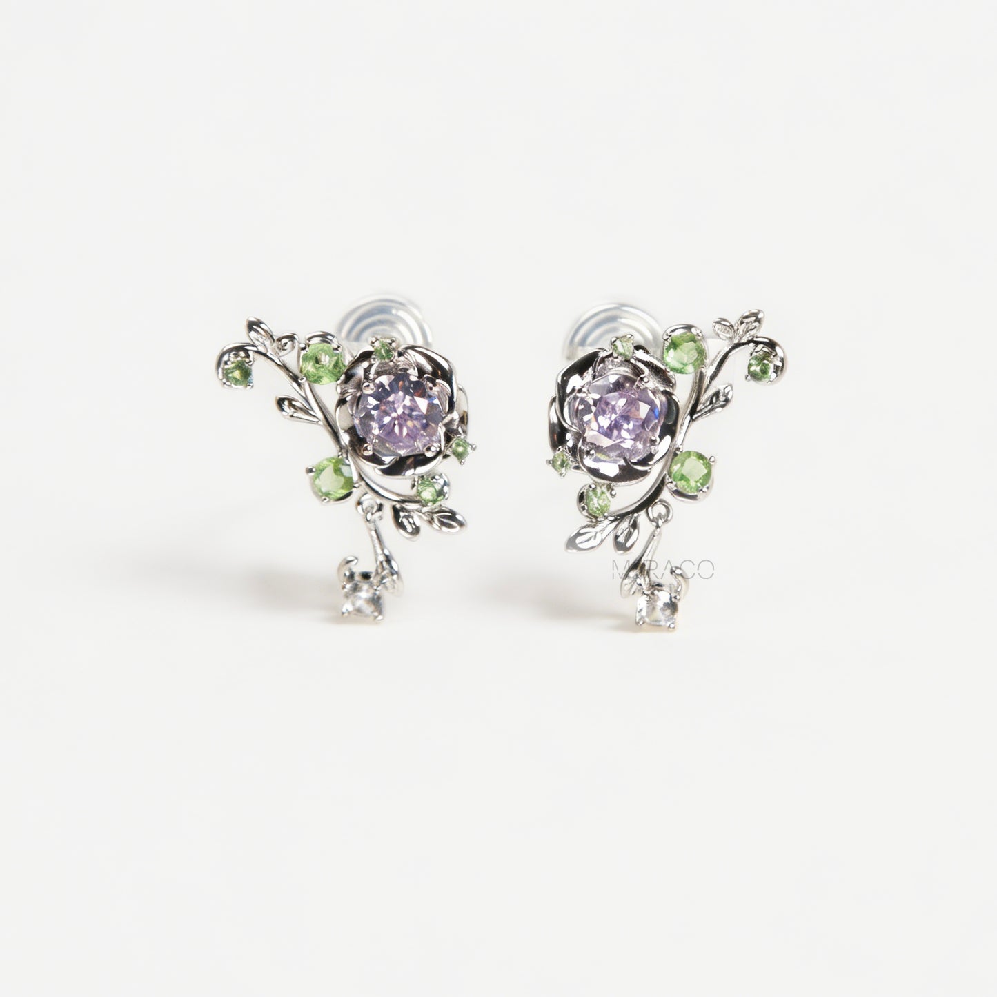 Pair of silver-tone floral clip-on earrings featuring a lavender center crystal, green leaf accents, and comfortable invisible coil back closures.