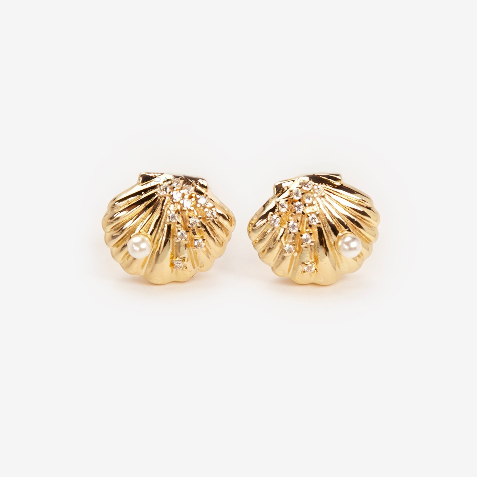 Pair of gold-tone scalloped seashell clip-on earrings featuring a small pearl and pavé crystals with comfortable invisible coil back closures.