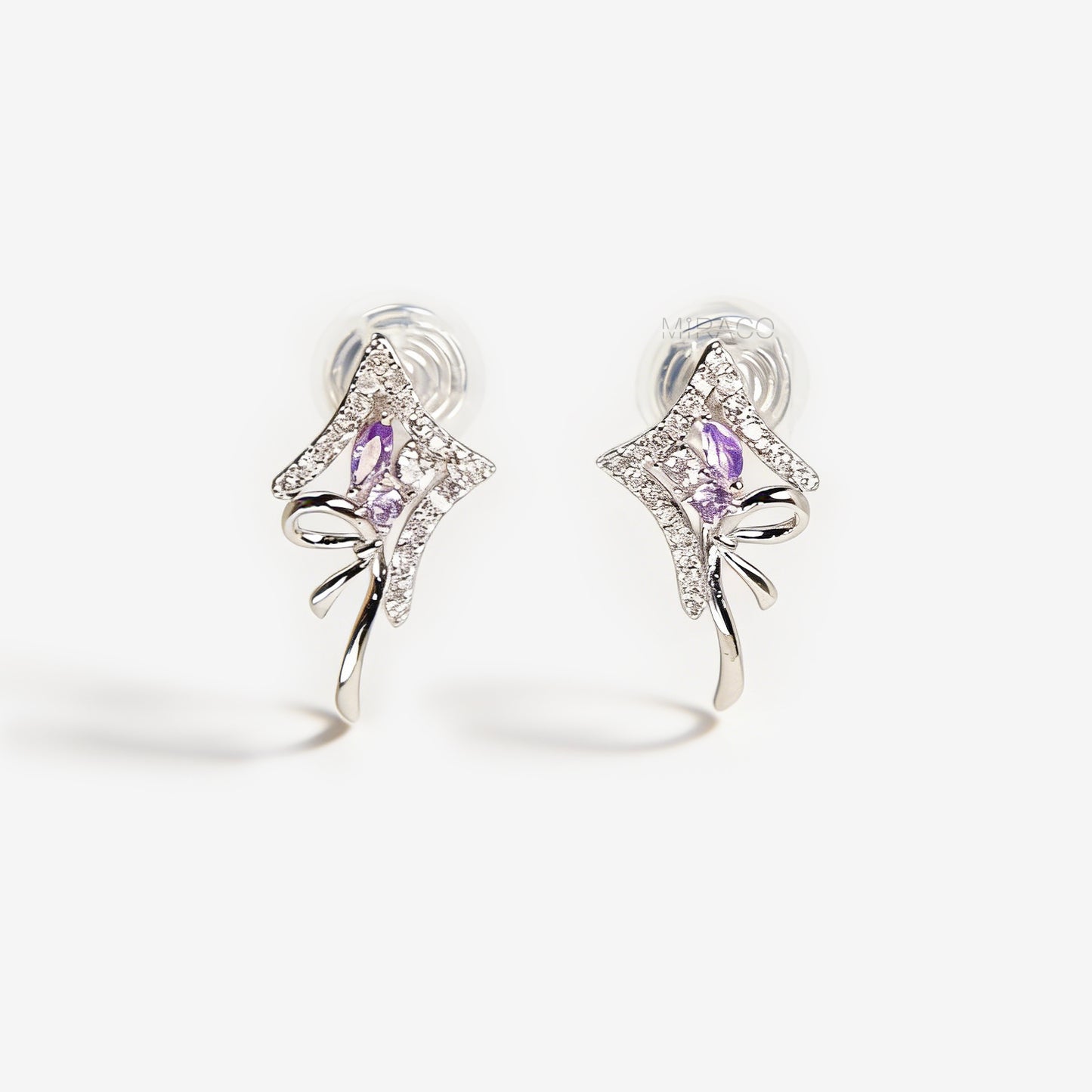 Pair of silver-tone bow-shaped clip-on earrings featuring purple amethyst stones, pave crystals, and comfortable invisible coil back closures.