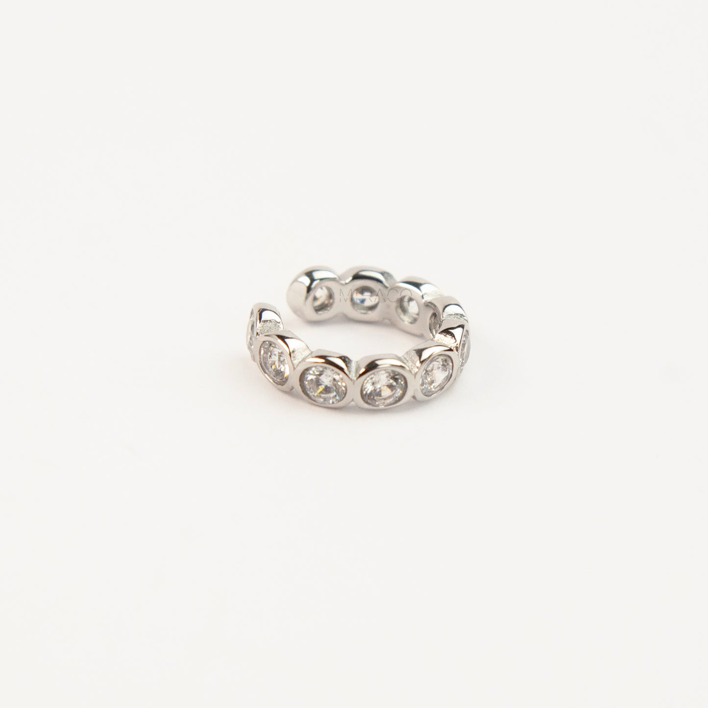 Silver ear cuff with embedded stones on a white background