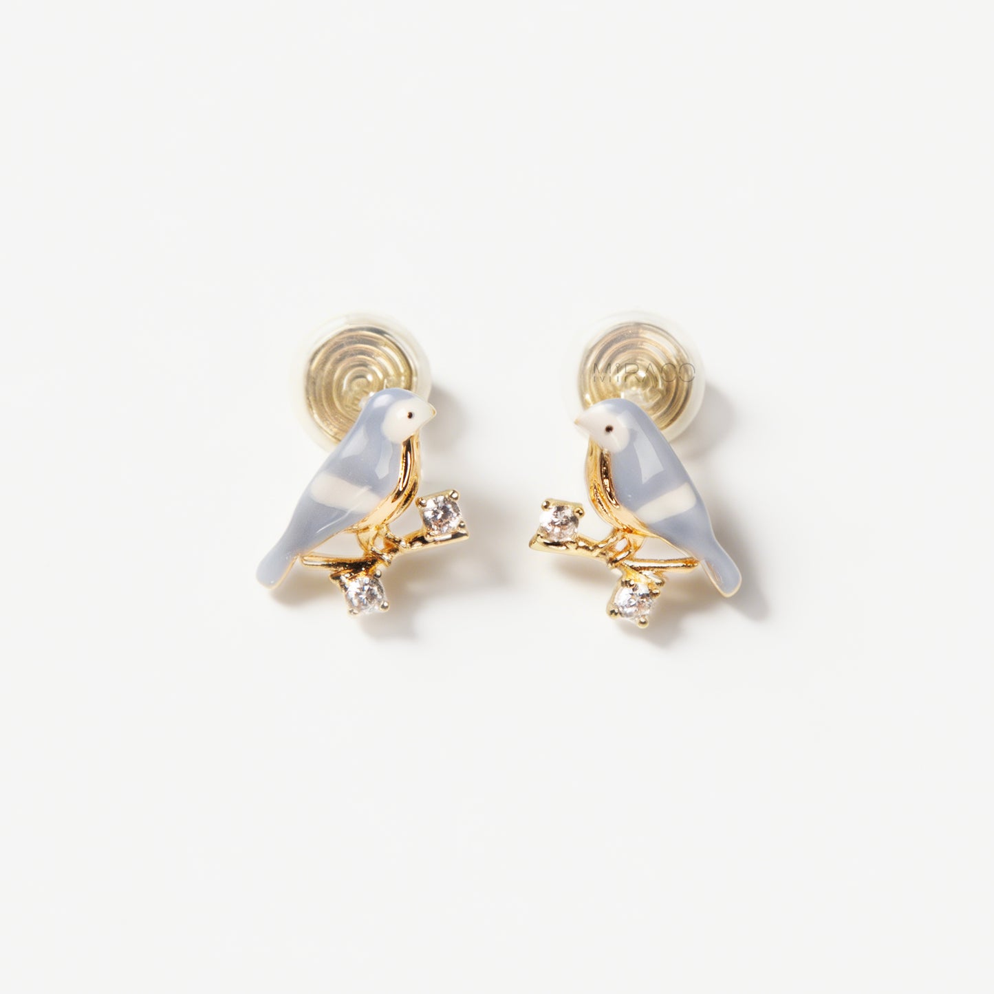 Pair of periwinkle blue enamel bird clip-on earrings perched on gold-tone branches with small crystals and invisible coil back closures.