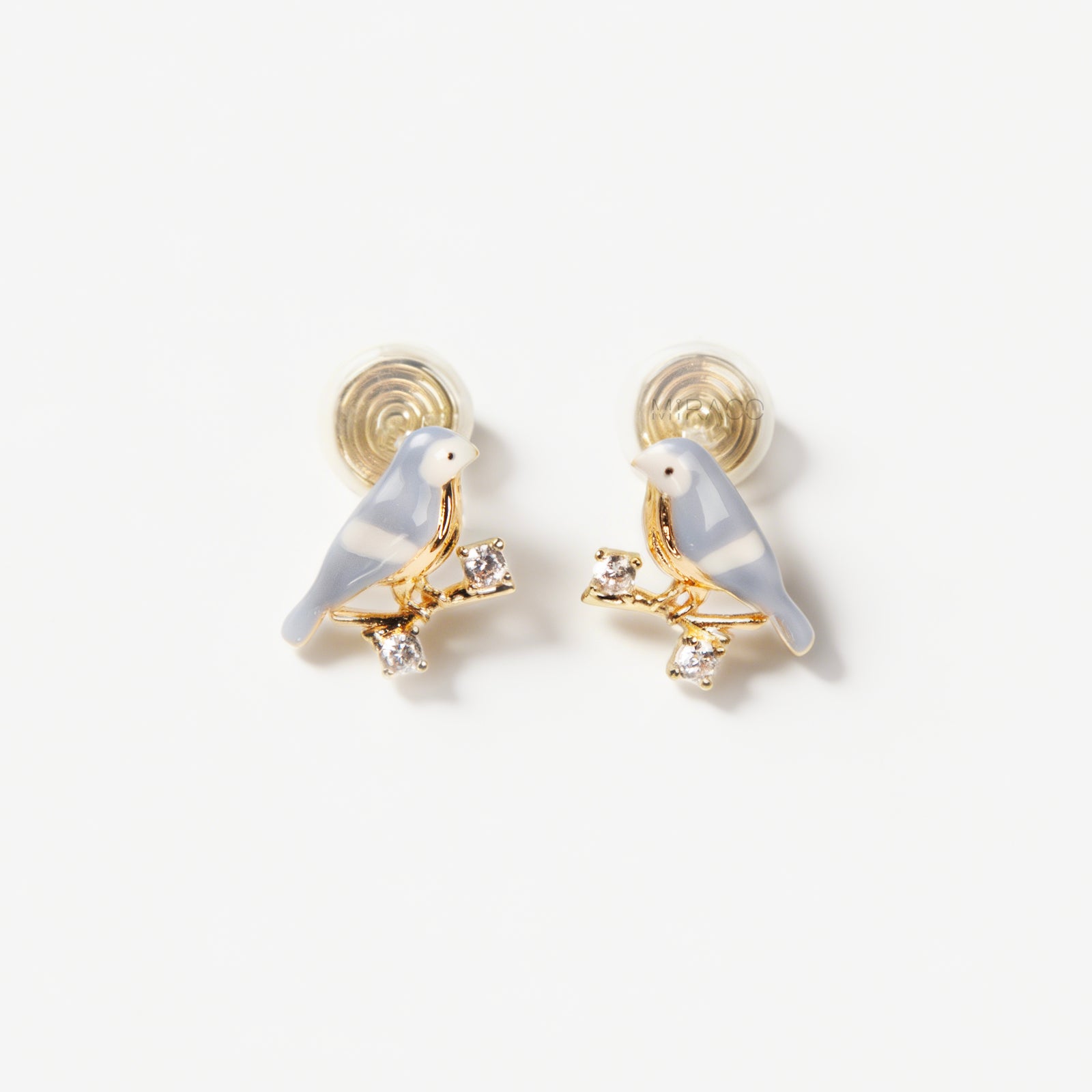 Pair of periwinkle blue enamel bird clip-on earrings perched on gold-tone branches with small crystals and invisible coil back closures.